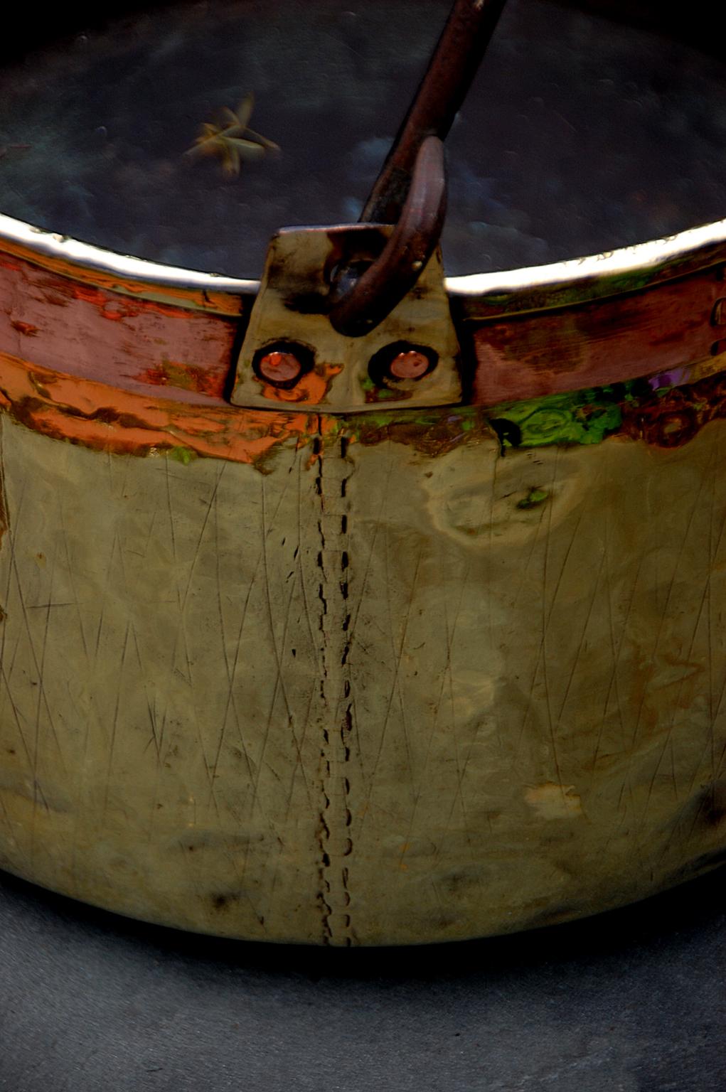 French or Flemish mid 19th century large brass cauldron with hand wrought iron swing handle. This heavy quality brass 18 inch dovetailed cauldron was made with a thick band of copper under the lip area to reinforce the structure of the cauldron.