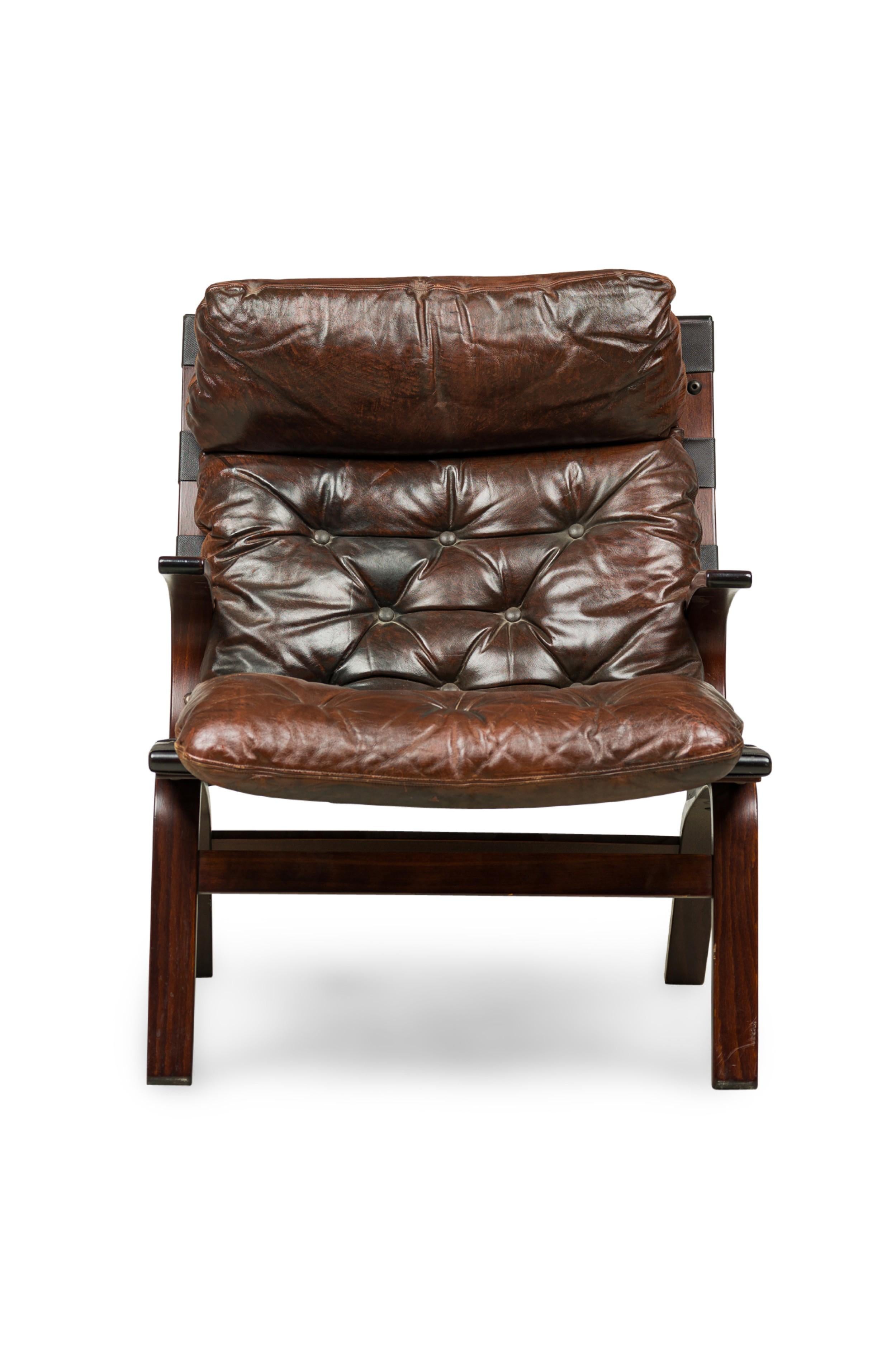 Scandinavian Mid-Century style bentwood armchair featuring curved arms and a brown leather button tufted cushion & headrest supported by a canvas sling back and seat, resting on four splayed legs with a glossy finish.
 

 Aging to leather
