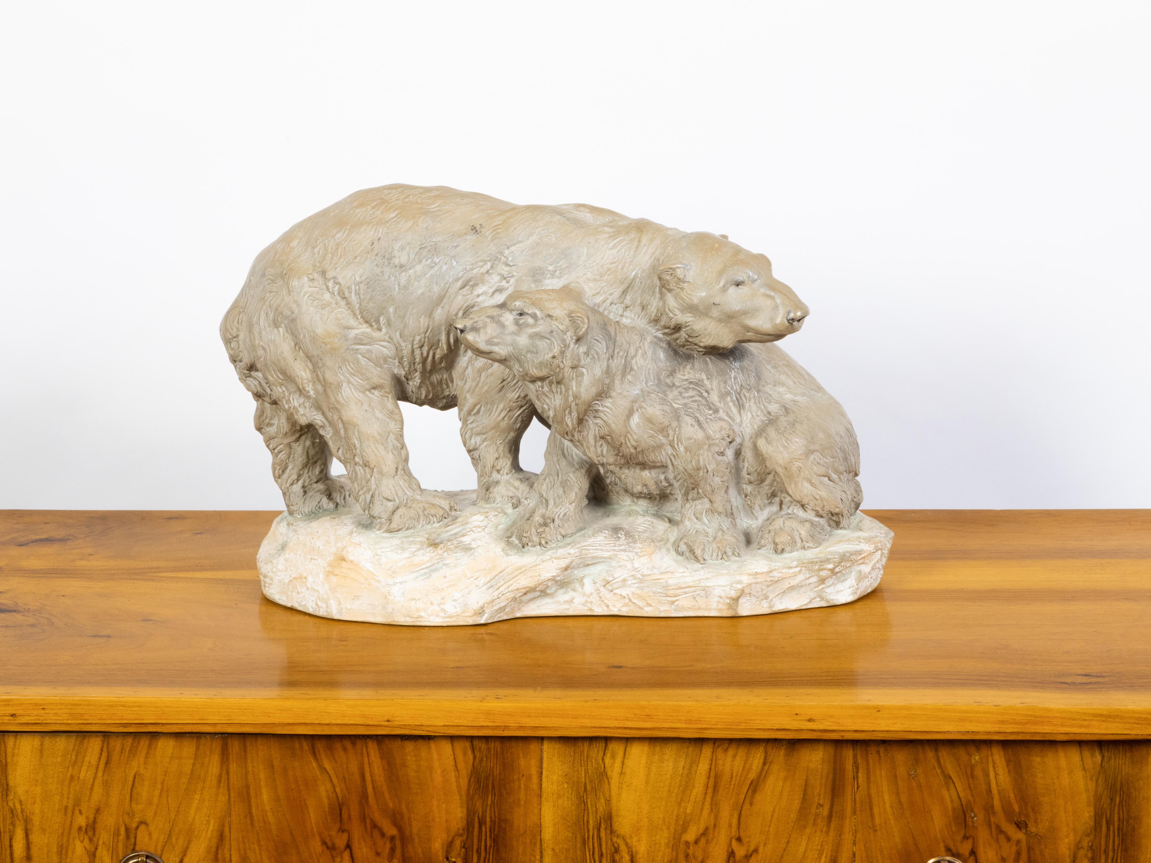 A Continental terracotta sculpture from the mid 20th century, depicting two bears on a base. Created during the midcentury period, this terracotta sculpture depicts an adult bear standing on an oval shaped base, protectively leaning over a smaller