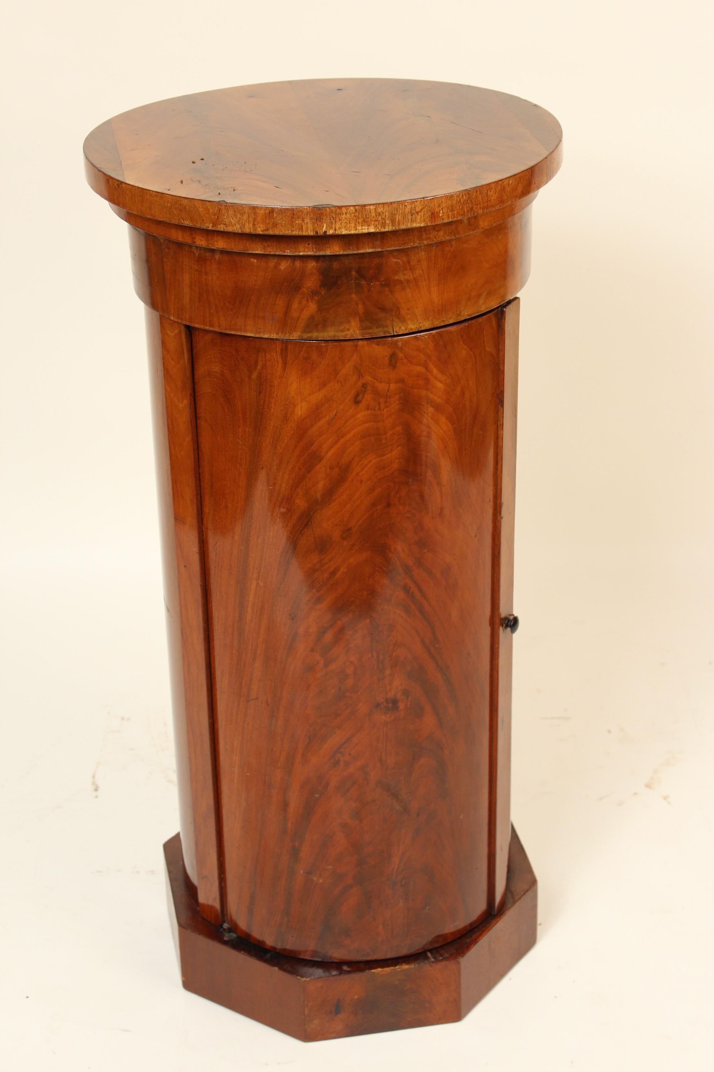 Continental neoclassical style flame mahogany cylinder form pedestal table, 19th century. The top opens and there is a door that opens.