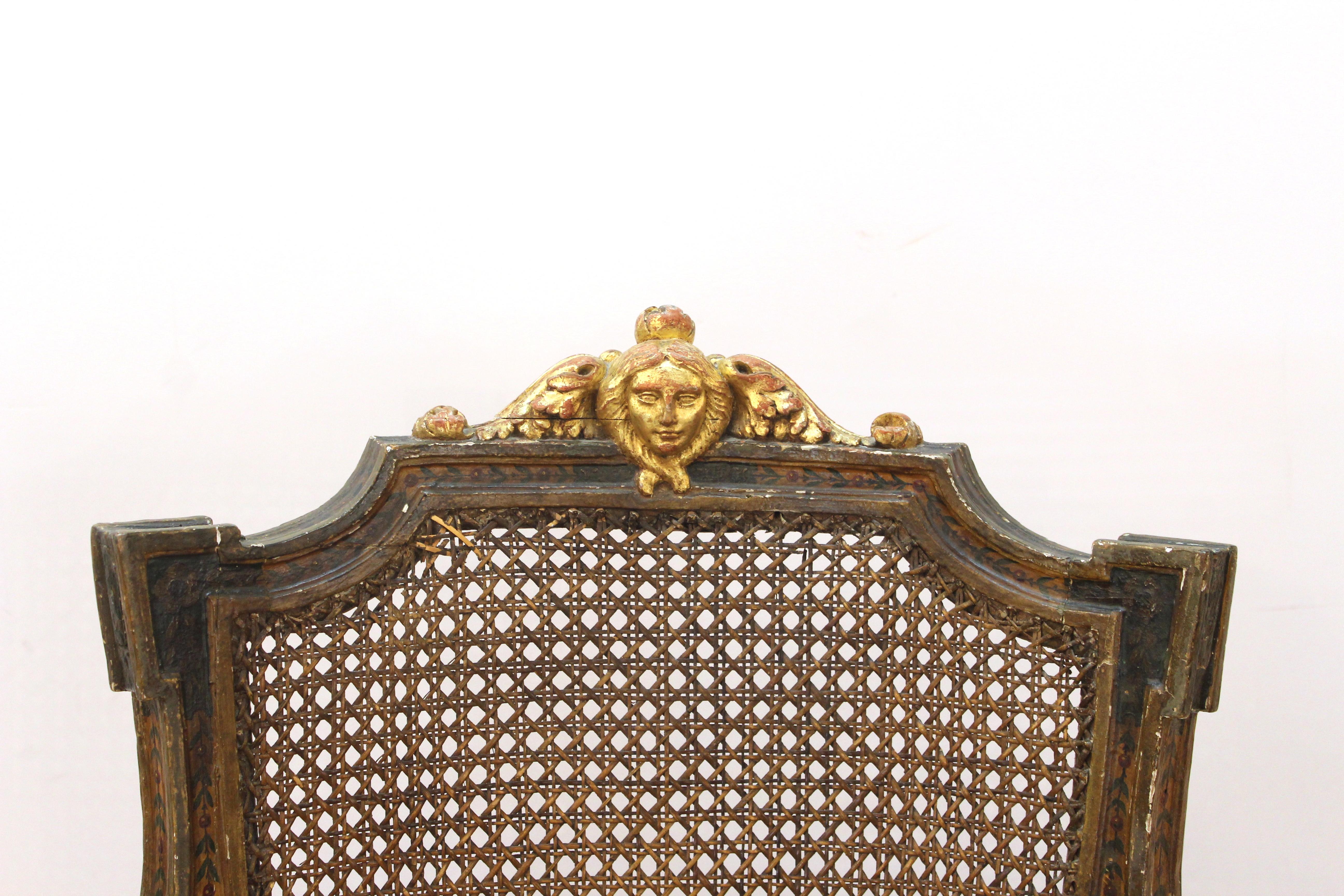 Antique Continental arm chair, likely late 18th century, parcel gilt and paint decorated, masque carved crest, acanthus leaf arms, caned back and seat and with upholstered cushion. 38.5