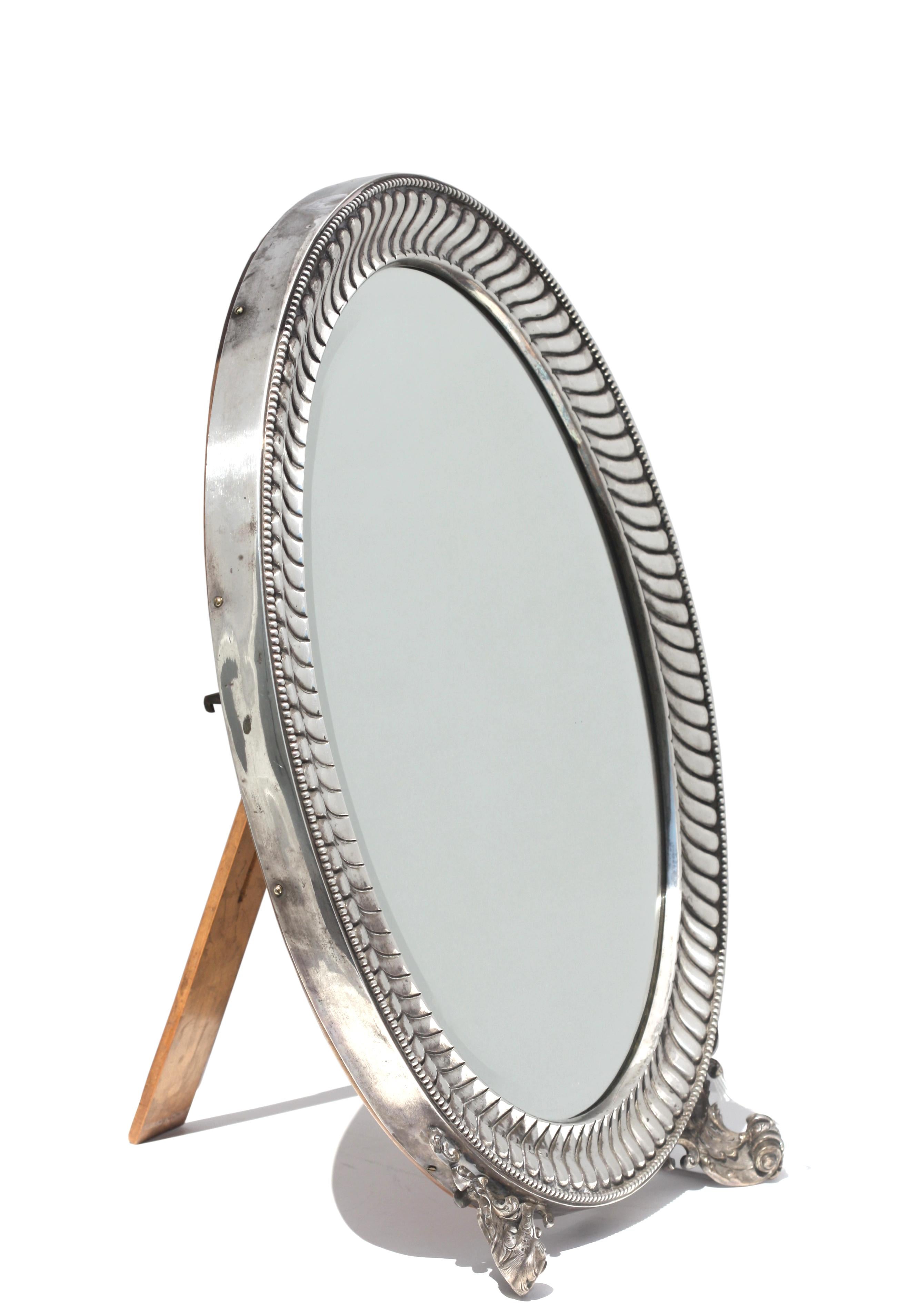 
Continental Neoclassical Silver Oval Dressing Mirror, 19th Century
Italian/French, marked. The oval swirled gadrooned surround with beaded border, on two foliate scrolled feet, with wood backing with hinged support. Height 18.75 in. (47.62 cm.),
