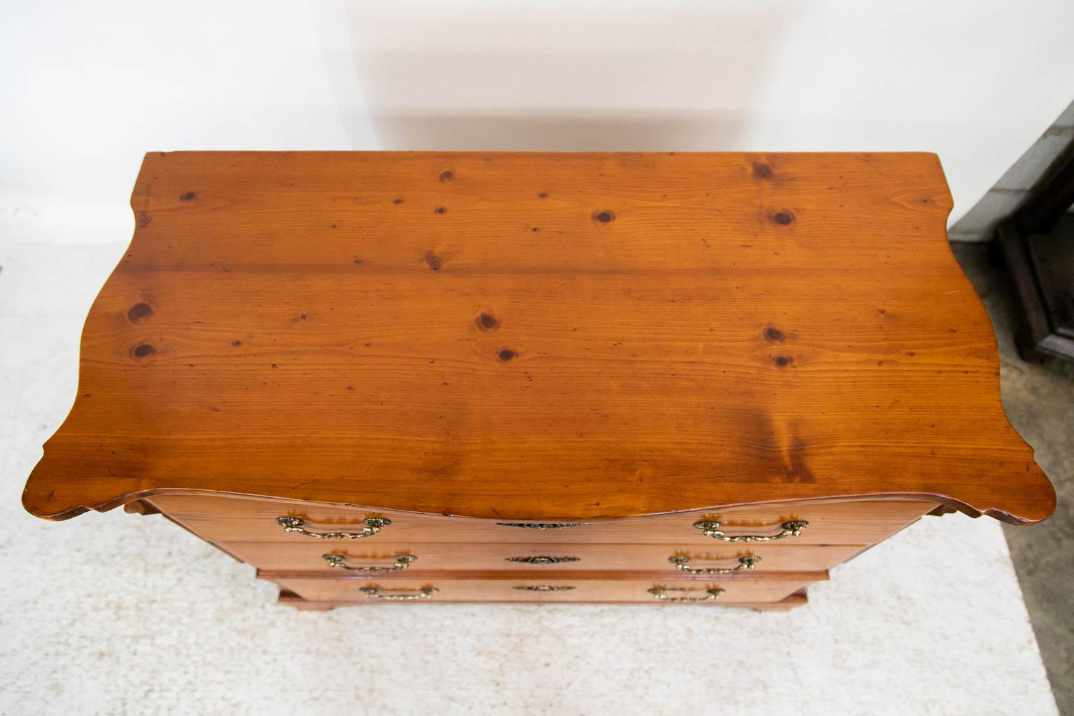 The locks on this chest are original. The brass hardware is later. The front and sides of the top have serpentine shapes. The front corners have a protruding arch over a carved supporting bracket. The sides have applied reed molding on the corner