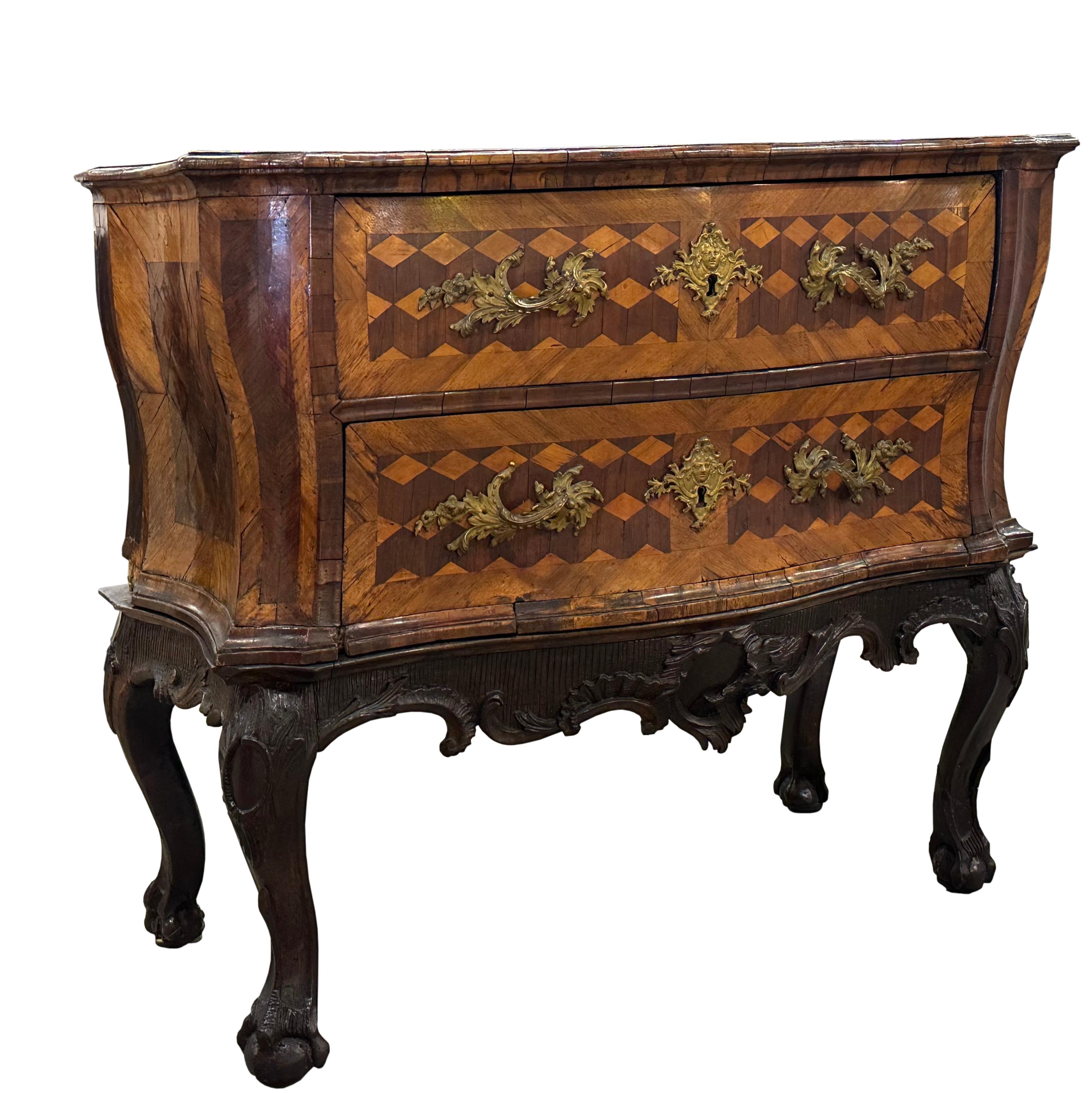 
Continental Rococo Walnut Parquetry Chest on Stand
Circa 1750, North Italian or South German. The serpentine molded top with walnut and fruitwood cube parquetry, the case with two drawers and with similar cube parquetry, on a rococo carved wood