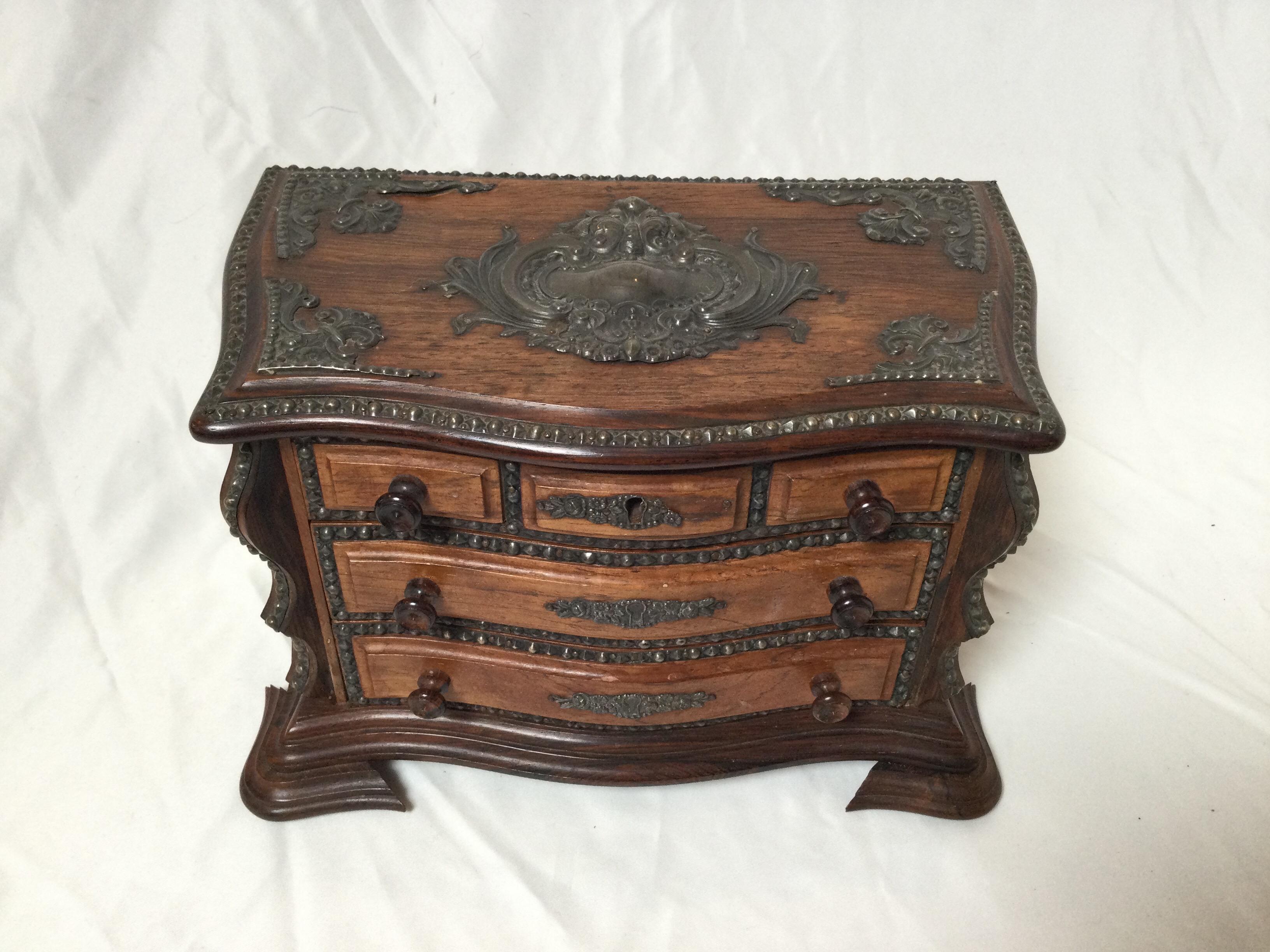Diminutive rosewood chest of drawers with dark silver mounts. The miniature chest with drawer front with two lower working drawers. The top section lifts to reveal storage. Perfect trinket jewelry box.
