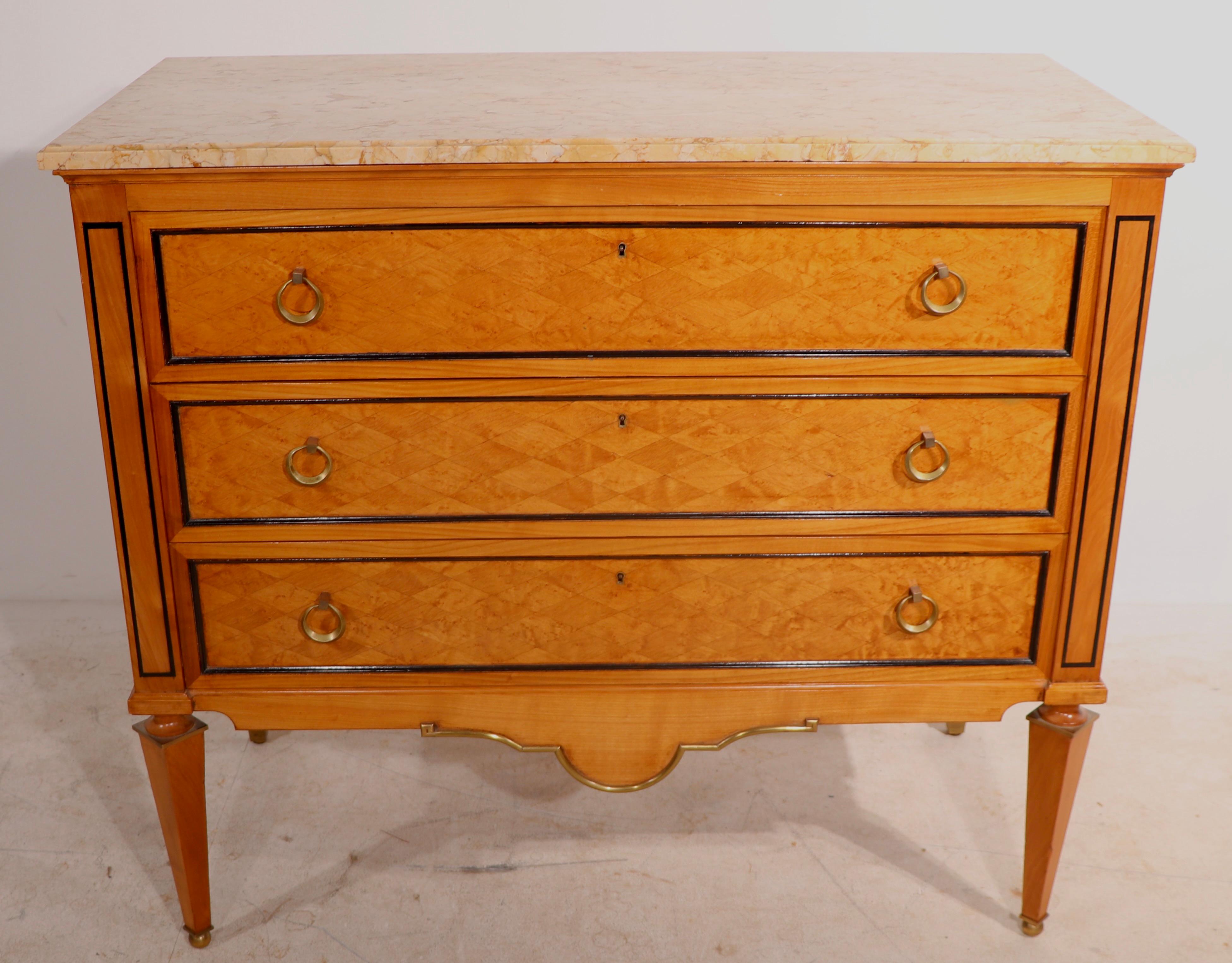Sumptuous three drawer satinwood marquetry case, with sophisticated brass trim and circular drop pulls, supports the thick marble top. We believe this chic commode was created in Italy circa 1940/1960's, however it is unsigned. This example is in