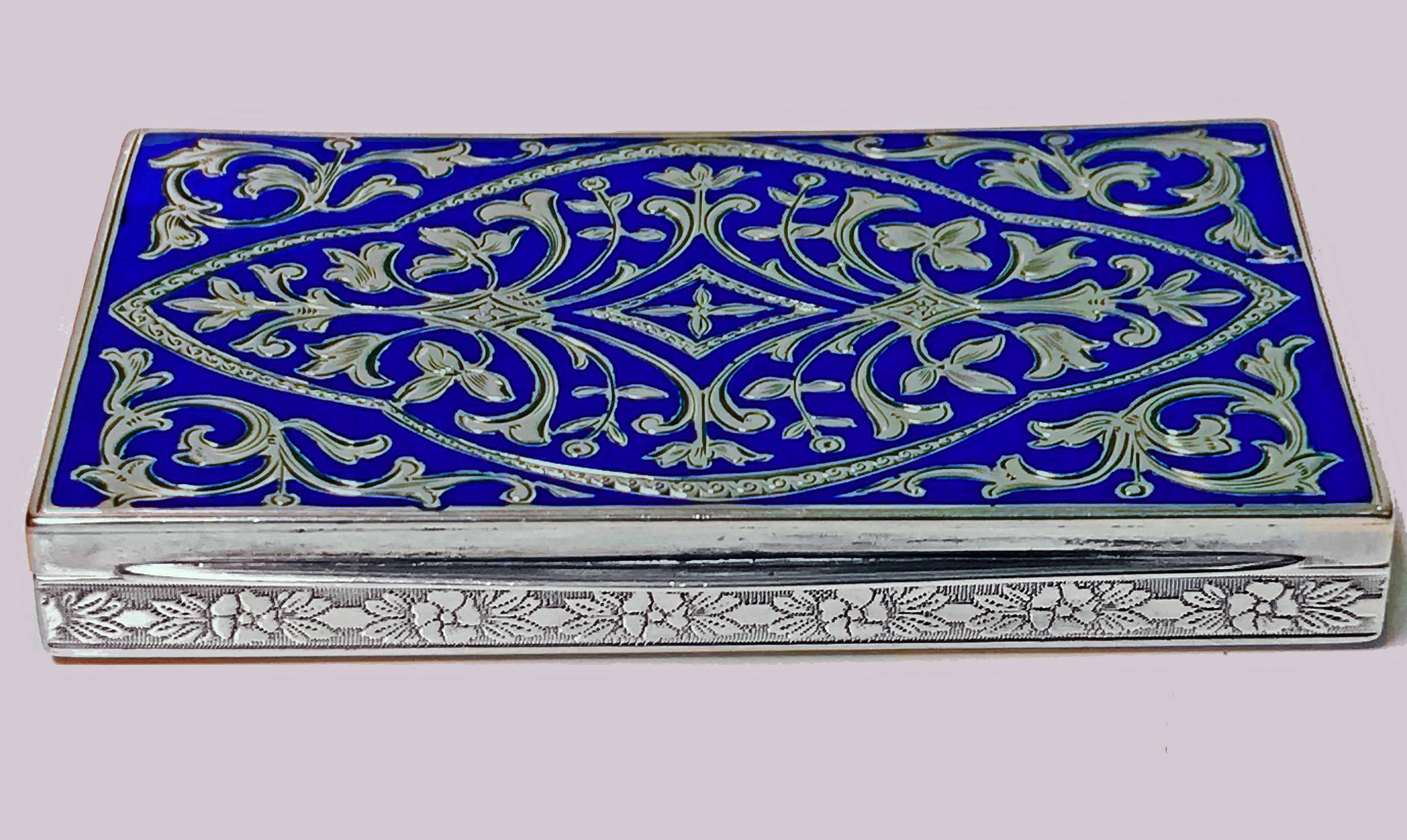Continental silver and royal blue enamel box, circa 1920. The rectangular shape box with front cover royal blue enamel with inlay of fleur de lys foliage silver decoration, the sides with engraved foliage rosette border against stippled background,