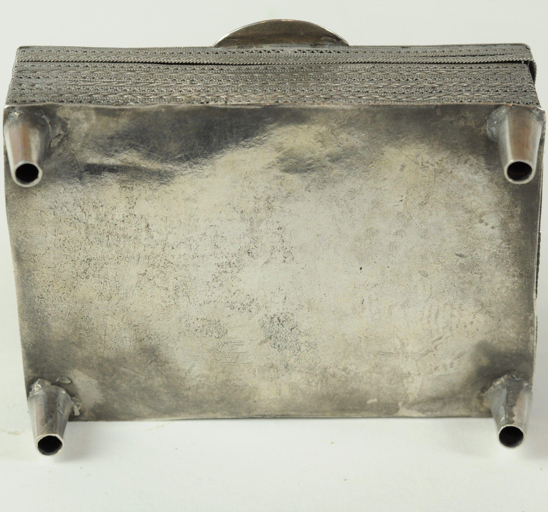 Scatola portagioie in argento fine costruita con filo d'argento fine attorcigliato e arrotolato in motivi geometrici.
Probabilmente continentale, fine del XIX secolo.
Alcuni danni come da foto. (Spaccatura lungo il bordo inferiore destro nel punto