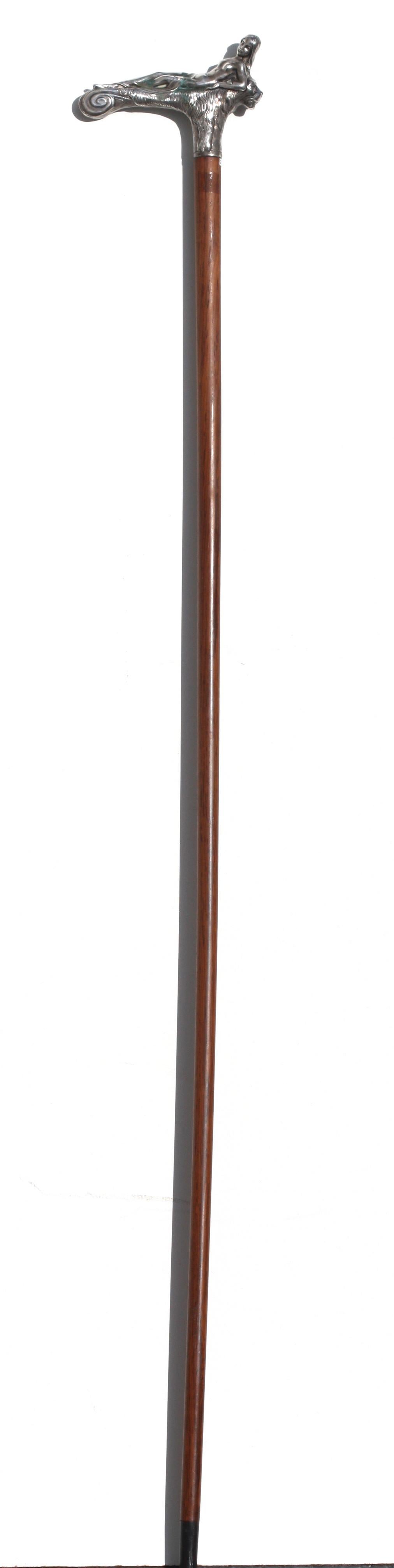 
Continental Silver Mounted Rosewood Gentlemens Walking Stick.
Late 19th Century, German or French. Appears unmarked. The handle cast as a lion surmounted by a recumbent scantily clad maiden, the rosewood shaft with a horn ferule. Length 36.25 in.