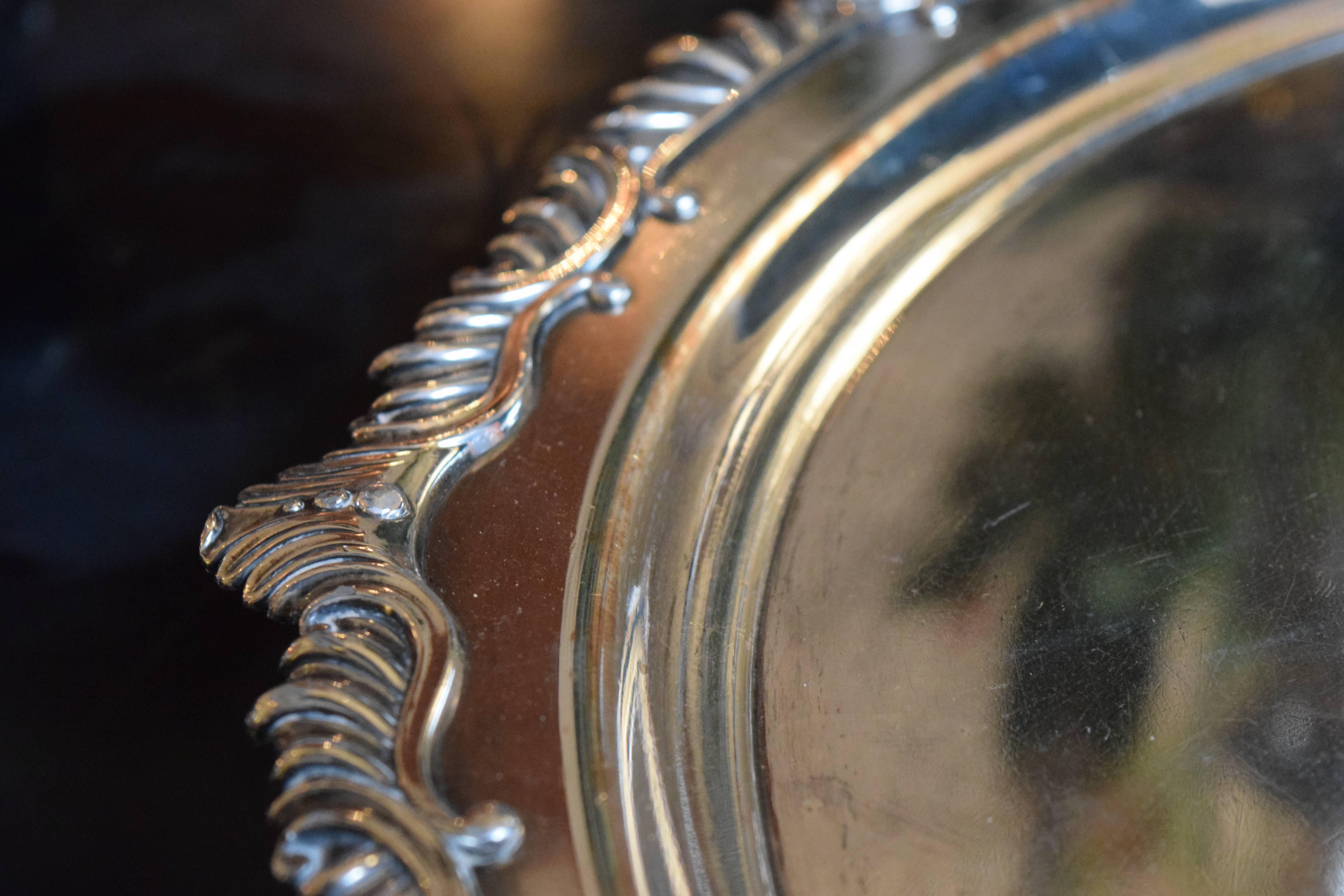 Continental silver plated round tray on four lion feet, the shaped borders chased with leaf scrolls, the centre engraved with a central coat-of-arms.