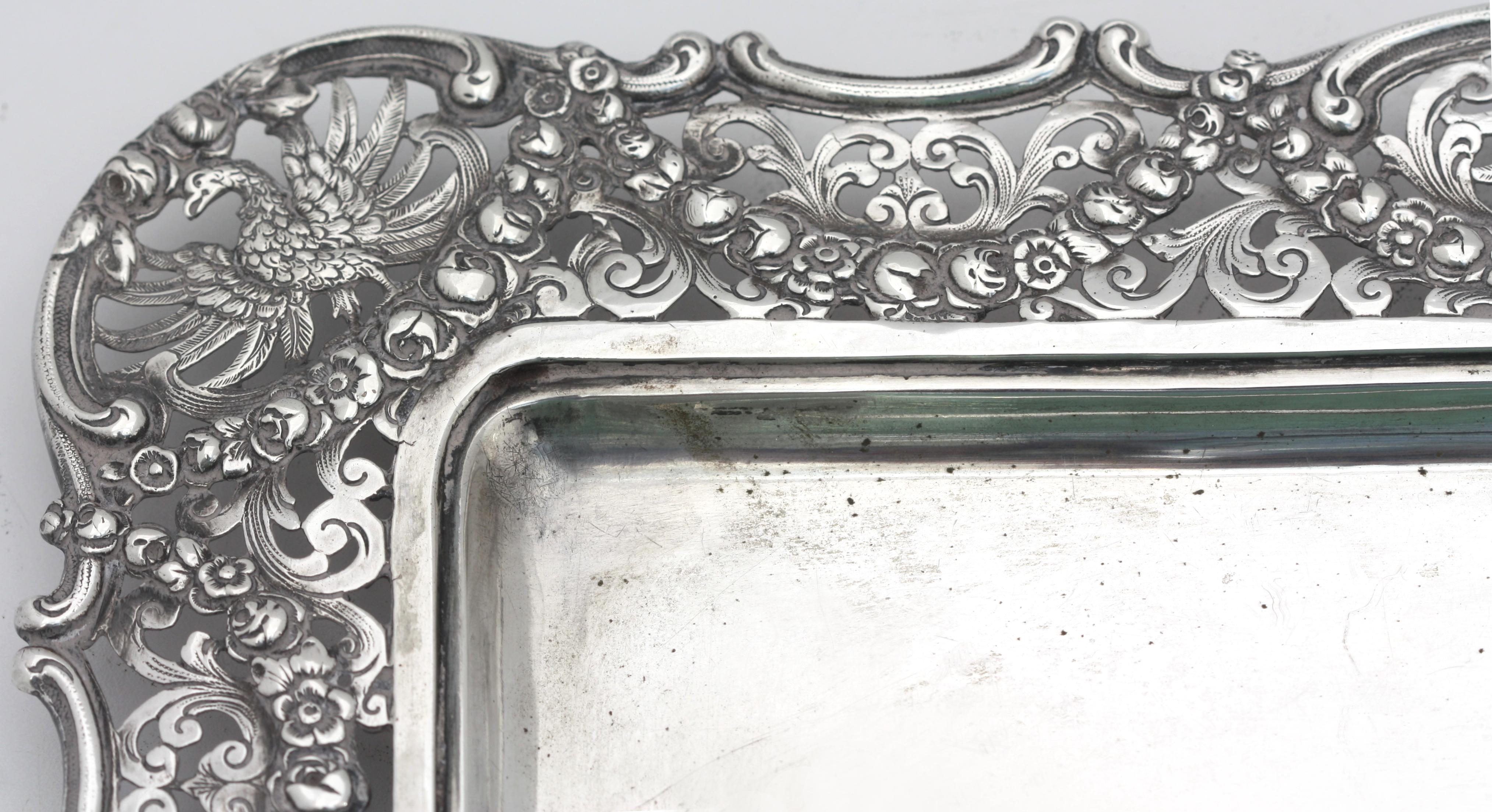 
Continental Silver Rectangular Tray, Probably German
Late 19th/early 20th Century. Marked 800, with three further indistinct marks., Rectangular, with a center recess, the pierced rim chased with displayed eagles with foliate and fruit garlands. 23