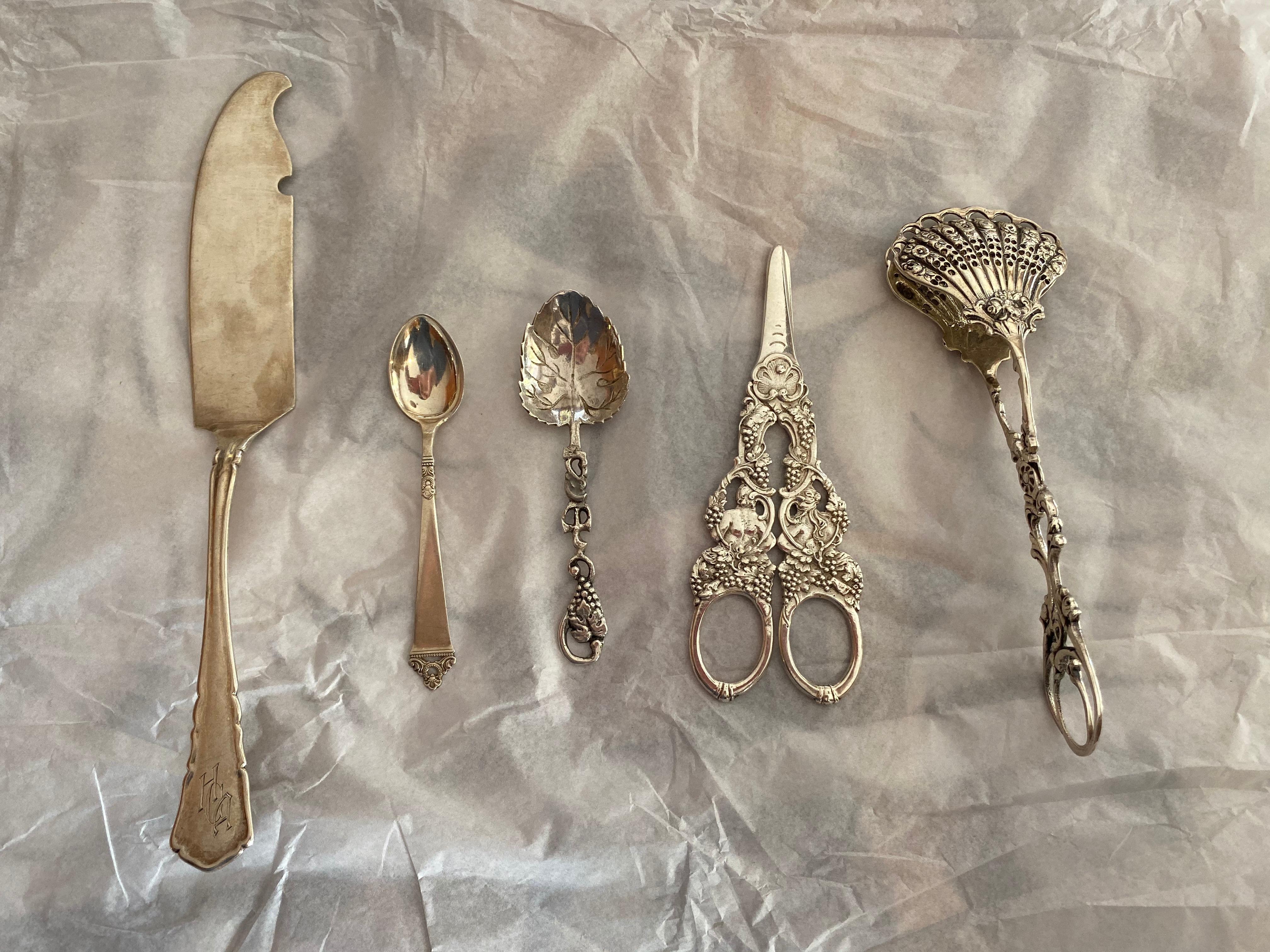 Group of five continental silver serving pieces, comprising large fish knife, tongs, grape scissors, two spoons, including Posen.
Measures: Knife 9.5