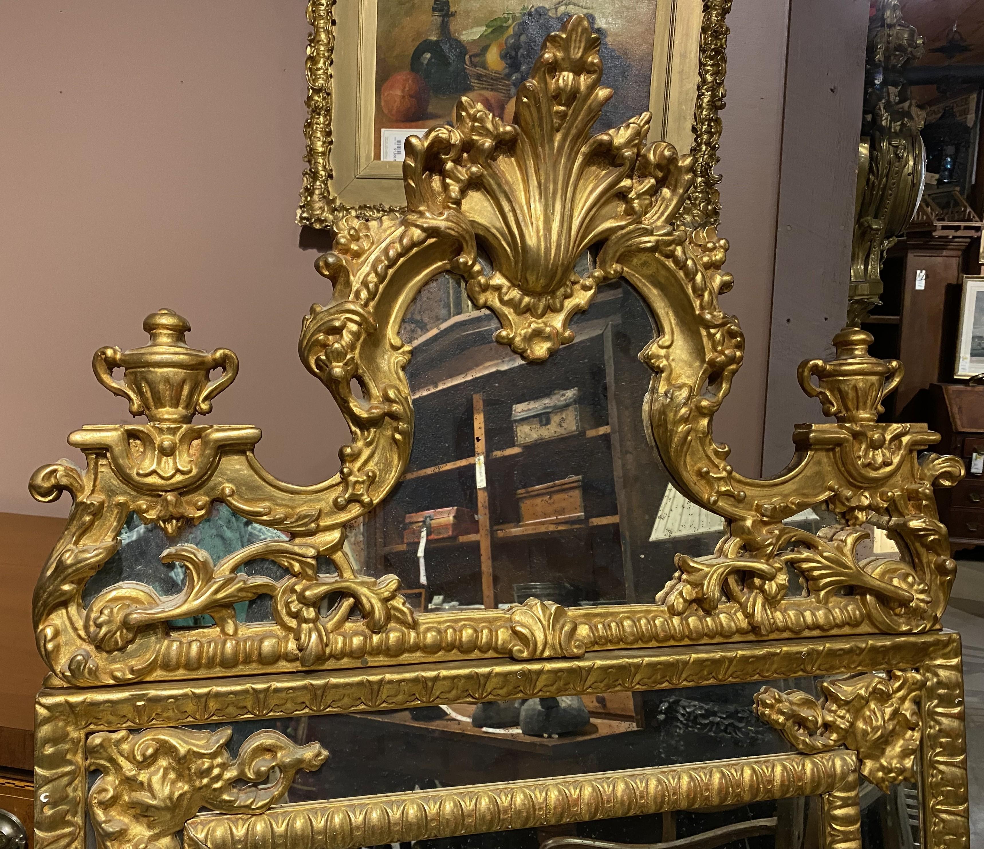Ein feiner handgeschnitzter rechteckiger Wandspiegel aus Vergoldungsholz im kontinentalen Stil mit Rokoko-Krönung, der in der Mitte eine Muscheldekoration aufweist, die von blattförmigen Akzenten in Urnenform flankiert wird, sowie eine antikisierte