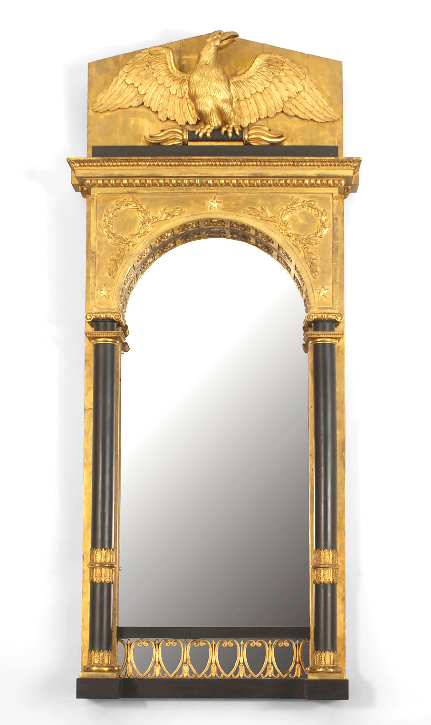 Miroir mural Empire suédois continental en bois doré avec côtés et garnitures de colonnes ébénisés et fronton d'aigle sculpté sur un miroir en forme d'arc.
 