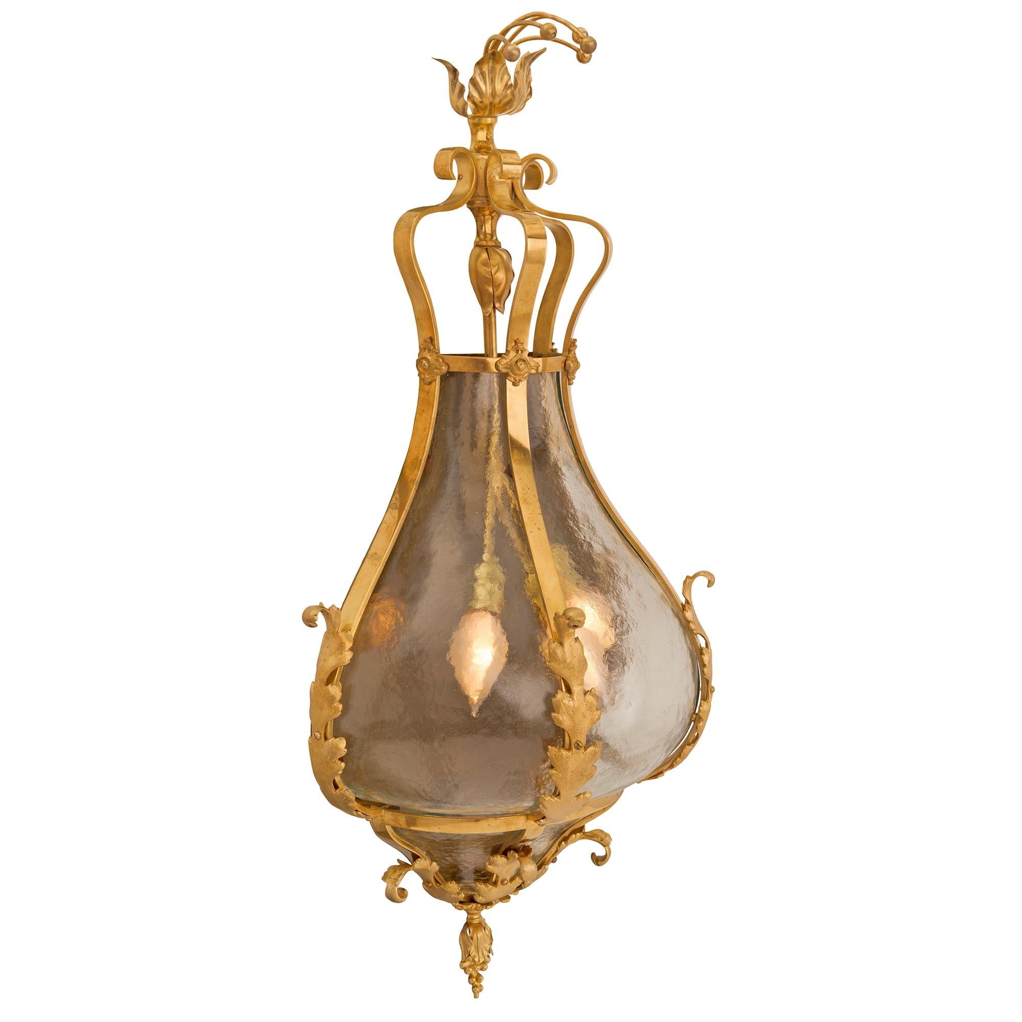 A beautiful and most unique Continental turn of the century ormolu and frosted glass sconce. The sconce is centered by a finely chased bottom foliate finial with charming leaves leading upwards. The original hand-blown frosted glass displays a