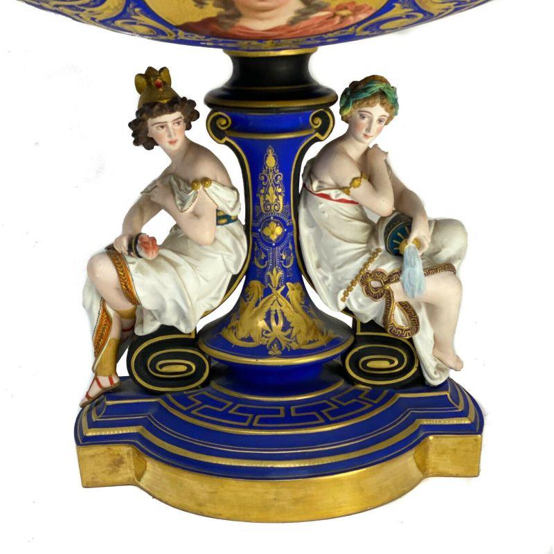 Continental Vienna Style Porcelain Centerpiece Pedestal Bowl, Early 20th Century

A cobalt blue ground with figural beauties sitting on the base. A hand painted portait of another beauty to the exterior of the bowl. Gilt enamel jewels to the stem.