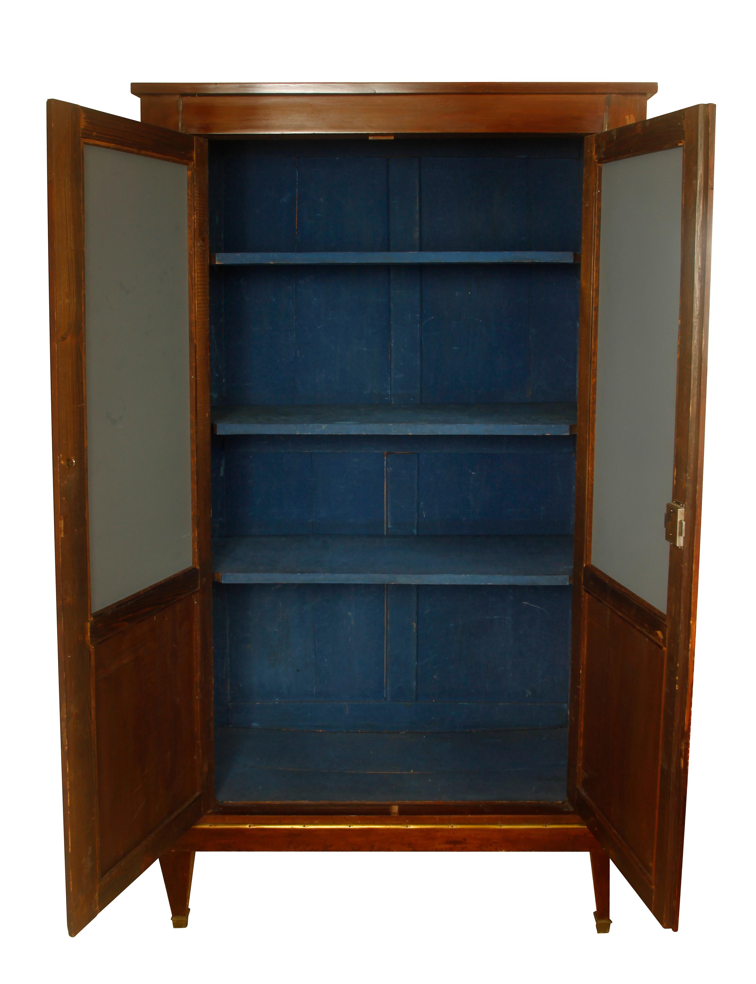 Continental armoire in walnut with antiqued mirror doors. Brass hardware and trim to the wood panels. Mirrored doors open to two interior shelves painted a beautiful shade of blue. Legs are tapered and straight.