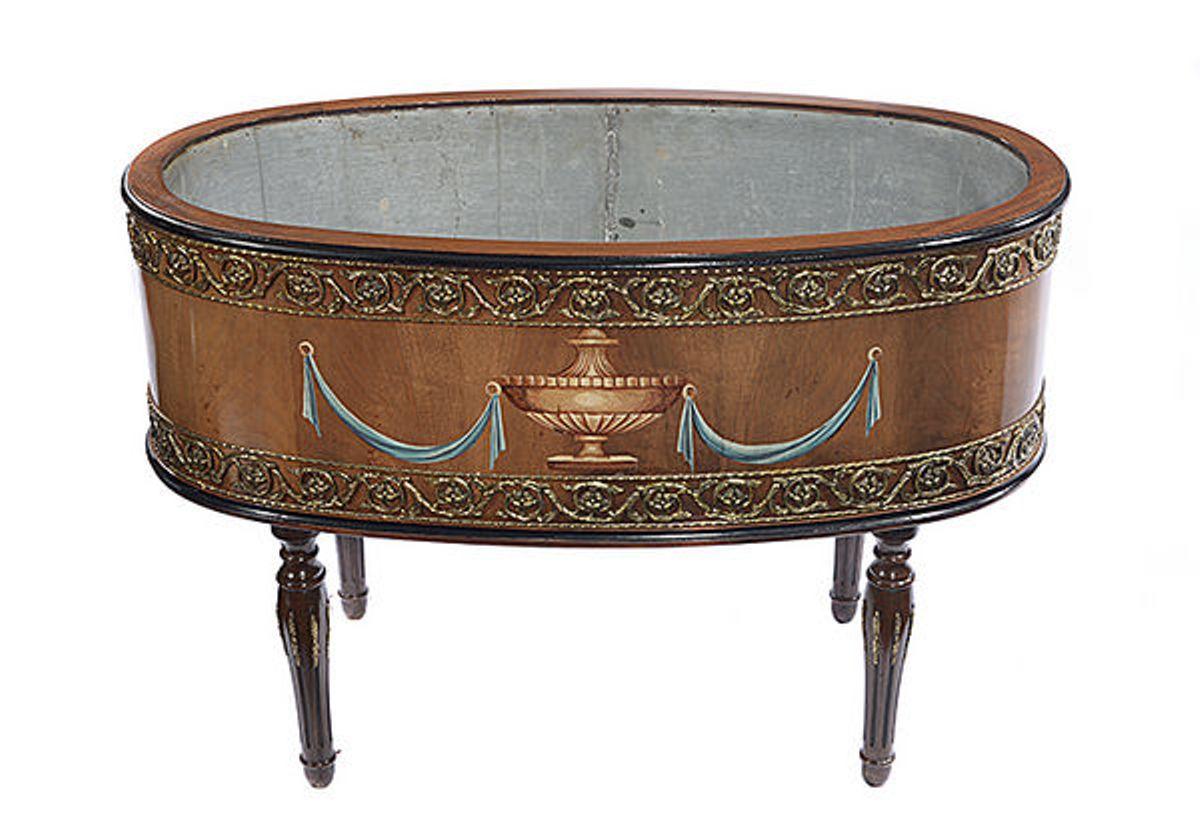 A cylindrically shaped Continental walnut plant trough with a zinc liner.
To each side a central hand painted urn with blue swags.
The top and base with a painted ebonized rim.
The whole with brass metal mounts in the form of a pierced band to