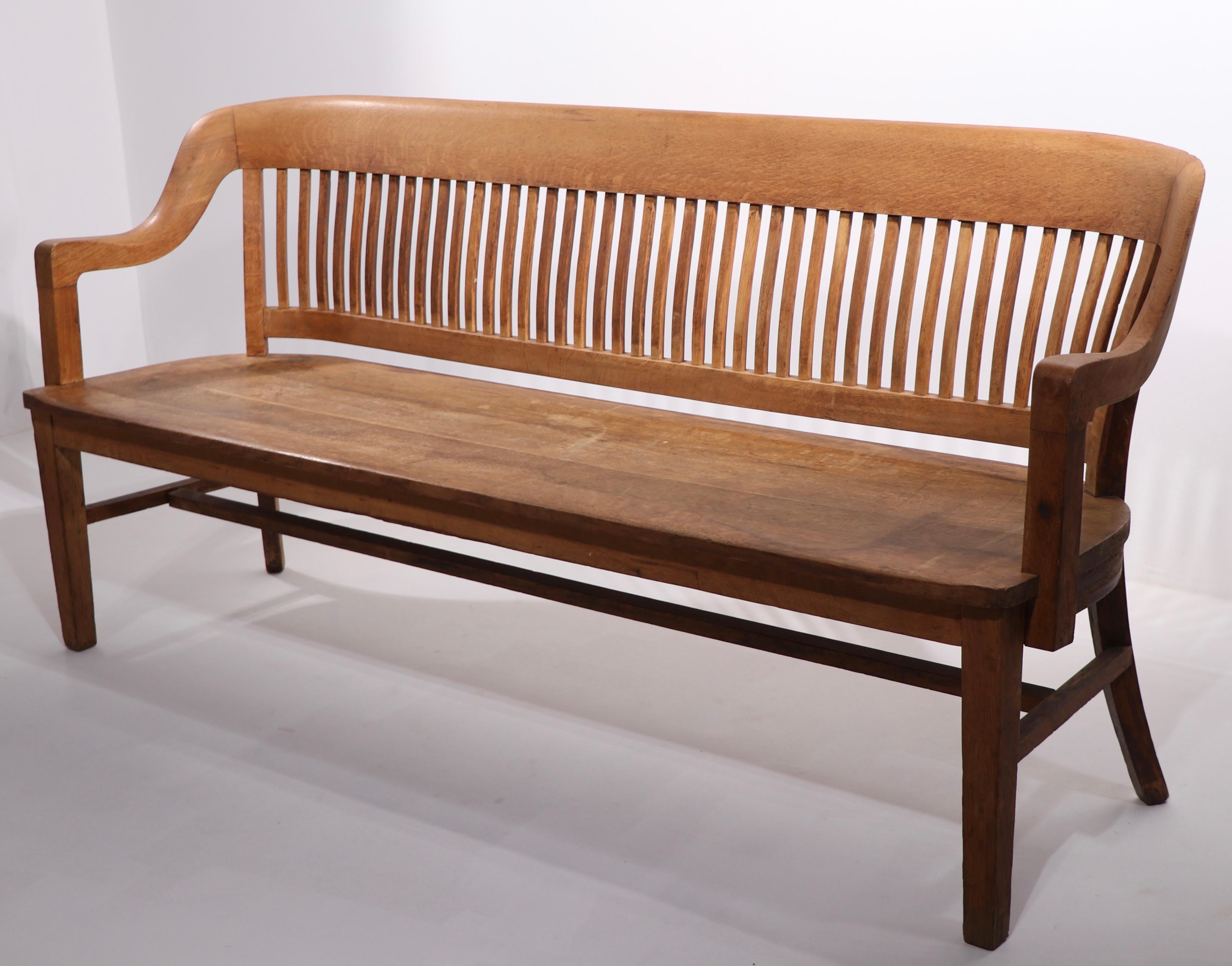 Classic courthouse bench by Gunlocke. This iconic American / English form will fit with Traditional, Industrial, or Modern interior spaces. This example is structurally sound and sturdy, it shows cosmetic wear to the finish, normal and consistent