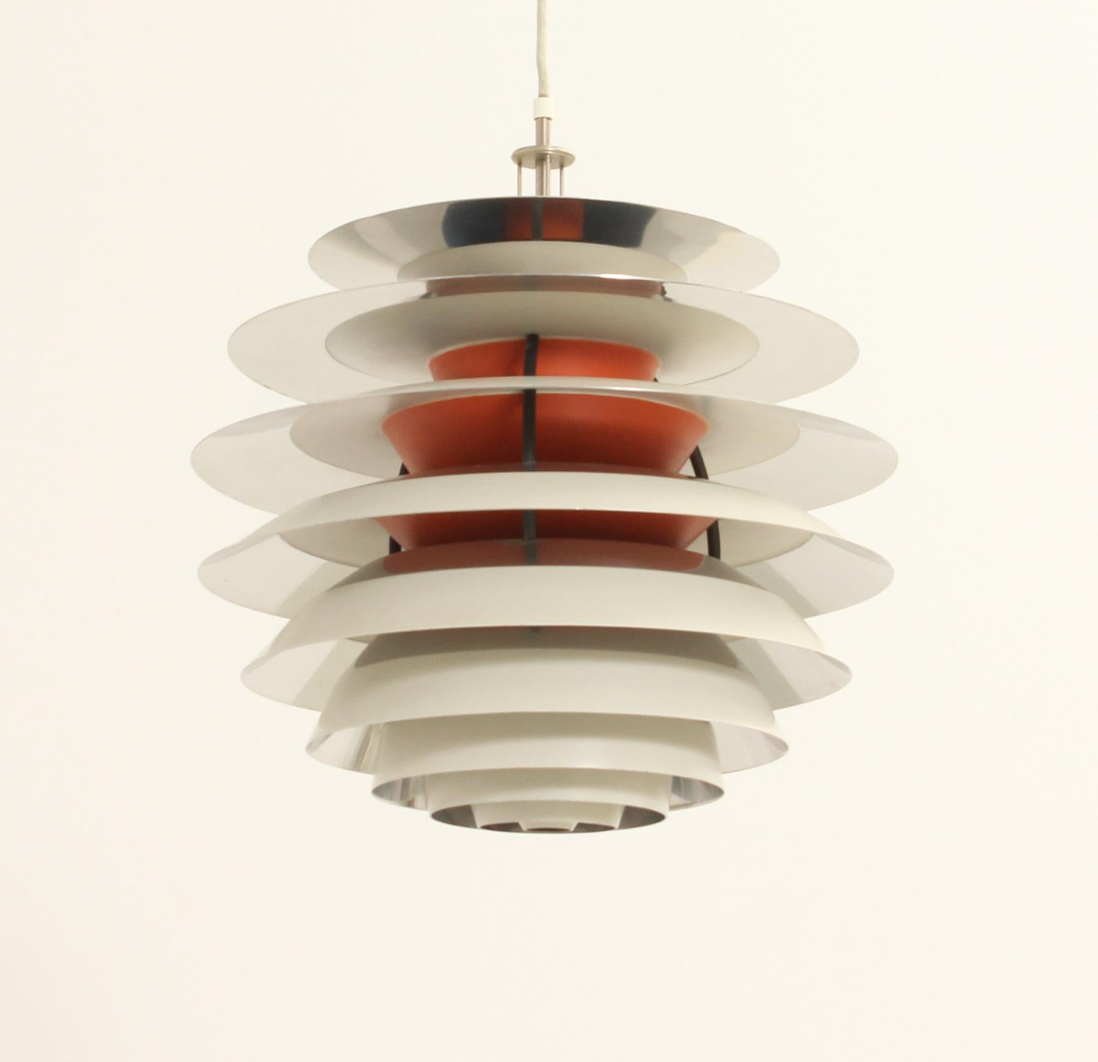 Contrast pendant lamp designed between 1958-62 by Poul Henningsen for Louis Poulsen, Denmark. Aluminum plates lacquered in white and nickel finish and interior orange lacquer. The light can be adjusted with the metal piece on top.