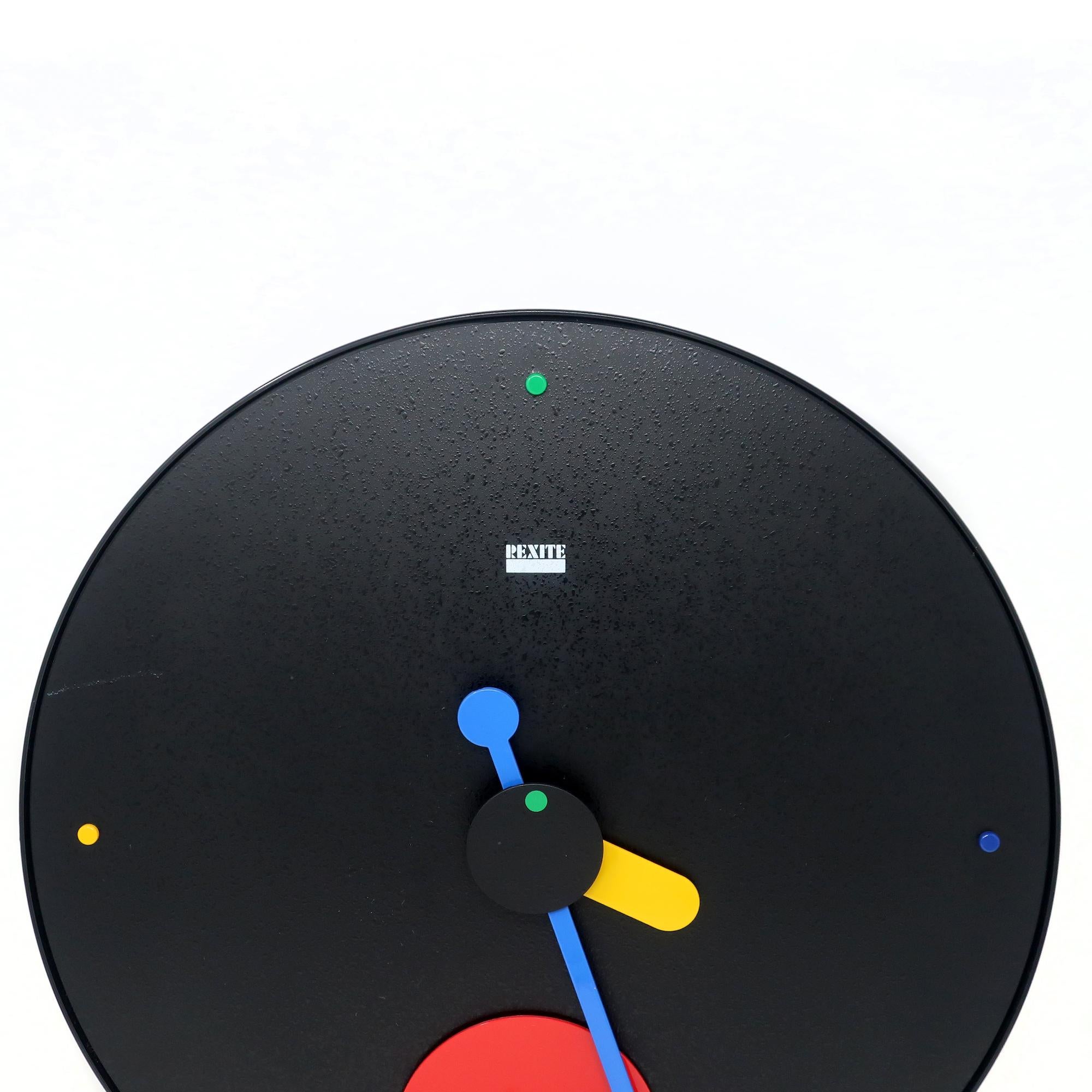 Designed by Raul Barbieri and Giorgio Marianelli for Rexite,the Contrattempo pendulum wall clock is postmodern design at its best. A black textured face, blue and yellow hands, and a red dot that swings back and forth as a pendulum. 

In good