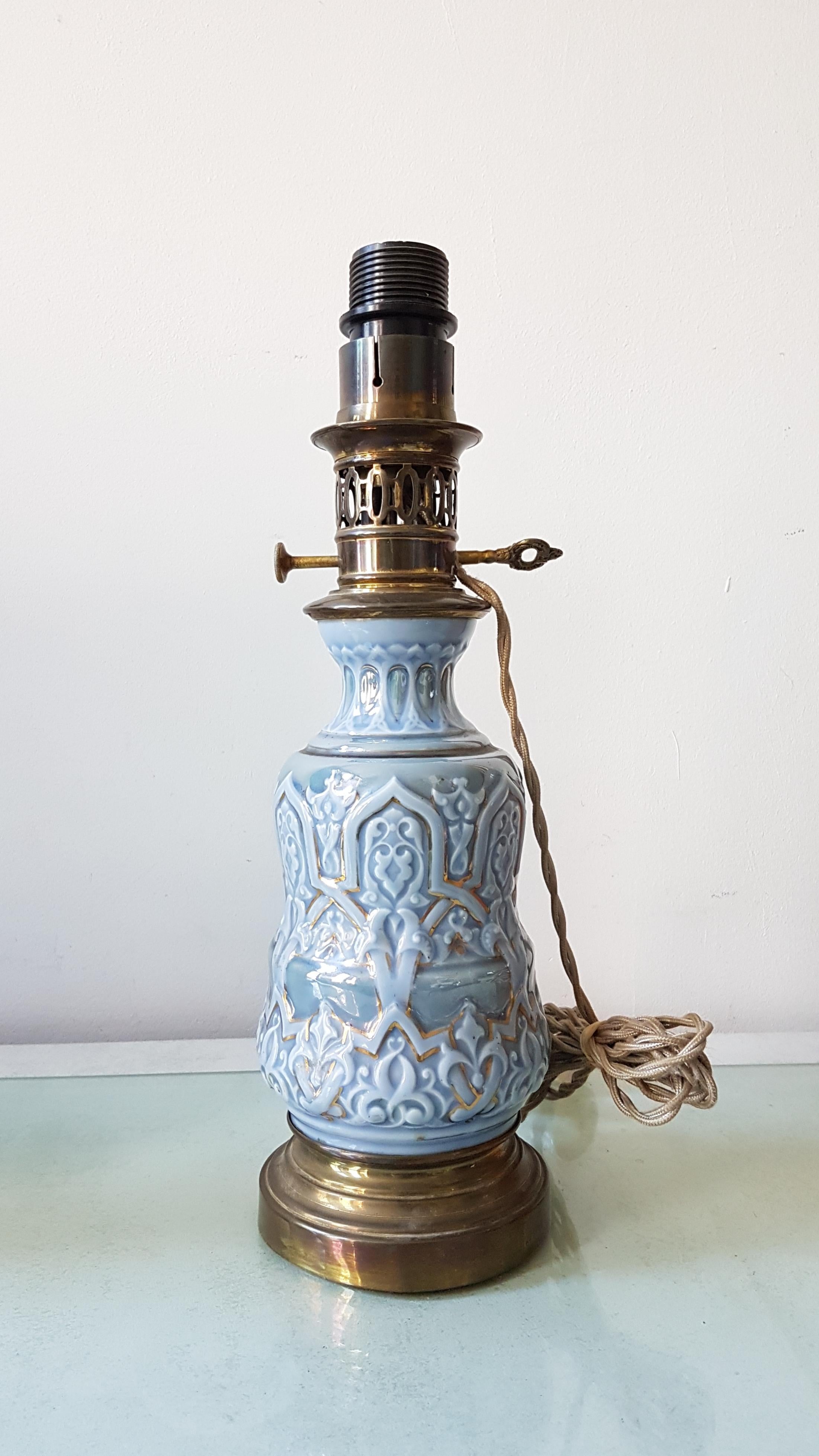 An elegant converted oil lamp made of ceramic in beautiful colors.
Late 19th century, converted kerosene lamp in blue with modeled details in turquoise and gold. Wonderful brass piecework chimneys and keys.

This lamp would look fine in all kinds