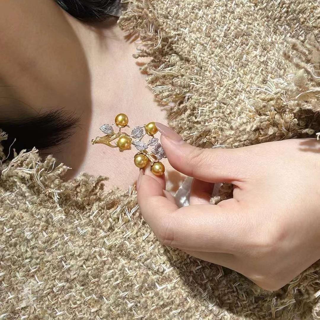 This versatile masterpiece features 8-9 mm golden South Sea pearls, prized for their radiant hue and captivating luster. Designed as both a brooch and a pendant, this piece showcases a textured floral branch motif crafted in 18K white and yellow