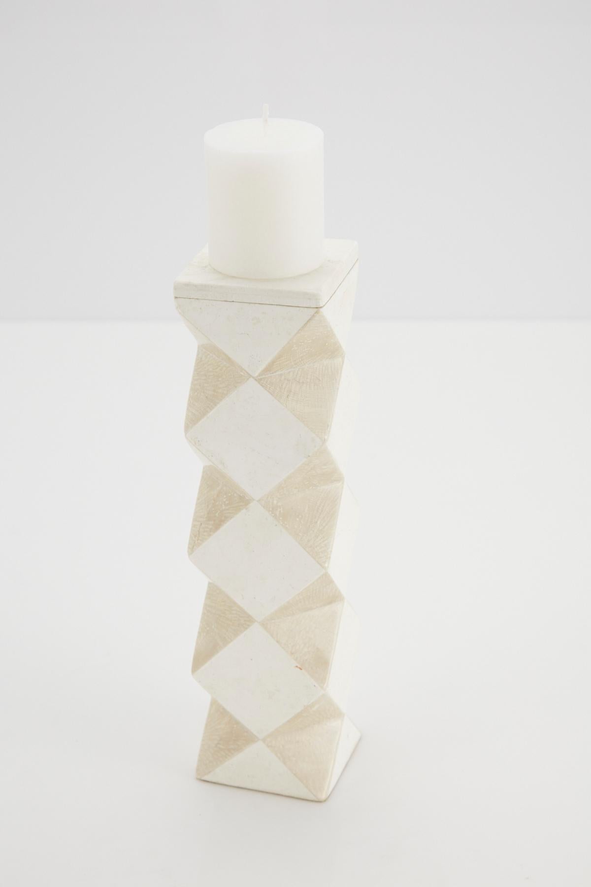 Medium-sized pillar candleholder. Body is comprised of a rectilinear cube with faceted sides, alternating white and beige tessellated stone. The top of this convertible candlestick is removable and can then be used as a vase.

All furnishings are