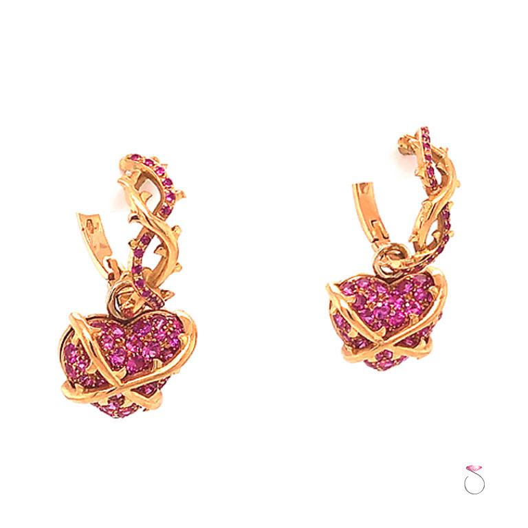 Stunning designer convertible hoop dangle earrings in 18k rose gold. These beautiful earrings feature two oval shape hoops in a vine design set with vibrant round pink Sapphires. Two removable heart charms hang through each hoop, set with round pink