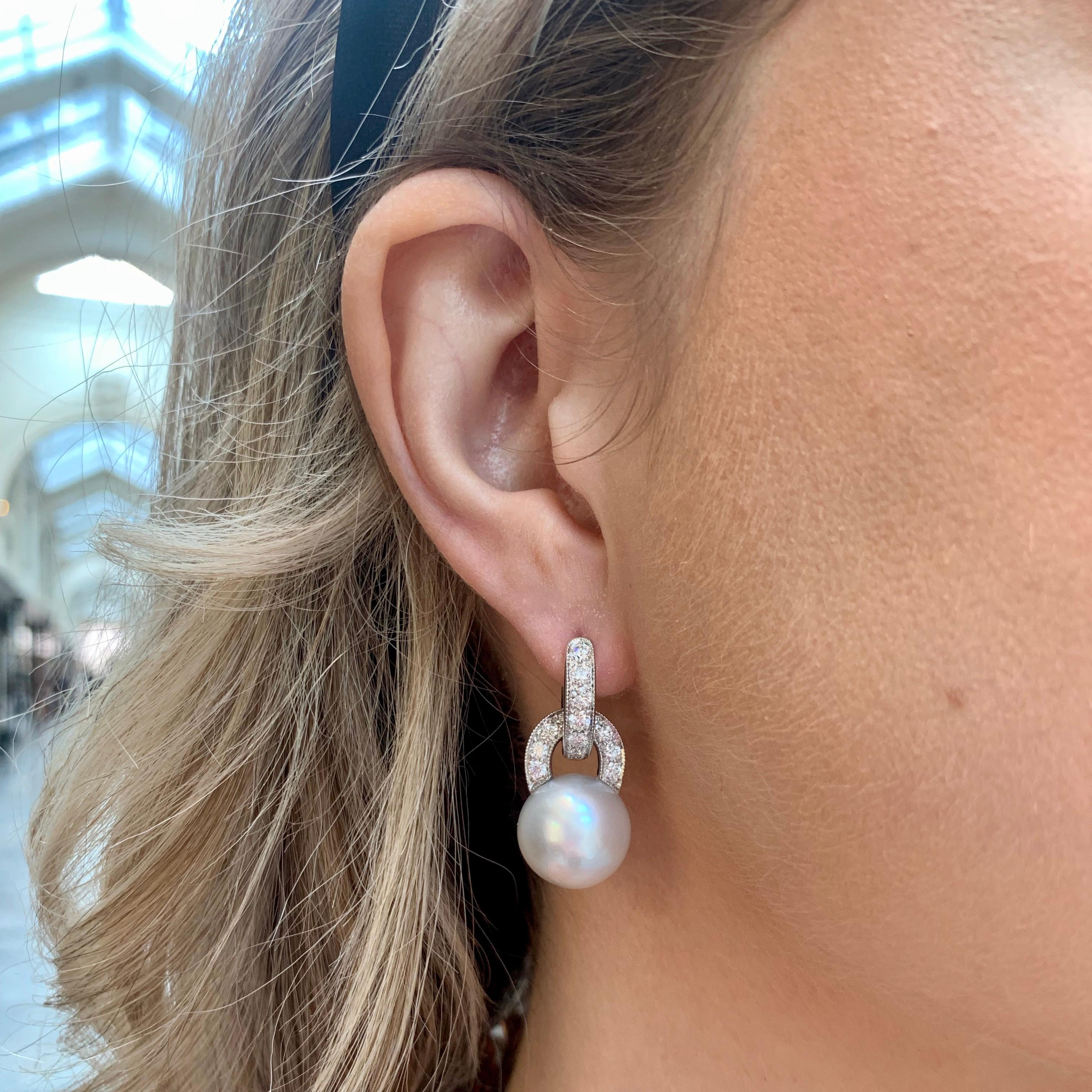  A beautiful pair of convertible pearl and diamond hoop earrings set in platinum.

Each earring is firstly composed of a beautiful hoop set with exactly 7 round brilliant cut diamonds. Hanging from this hoop is a 14-millimetre white cultured pearl