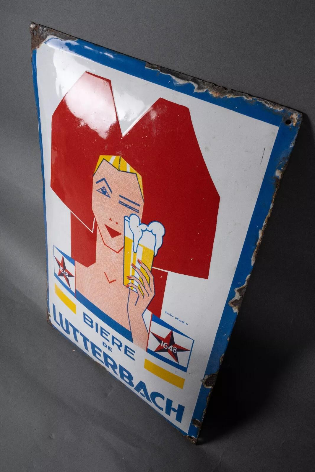 Cette plaque en émail est typique des années 1930, avec un motif très géométrique.

Il est signé André Stouls 21, et a été fabriqué par Email ALS. Le marquage indique 