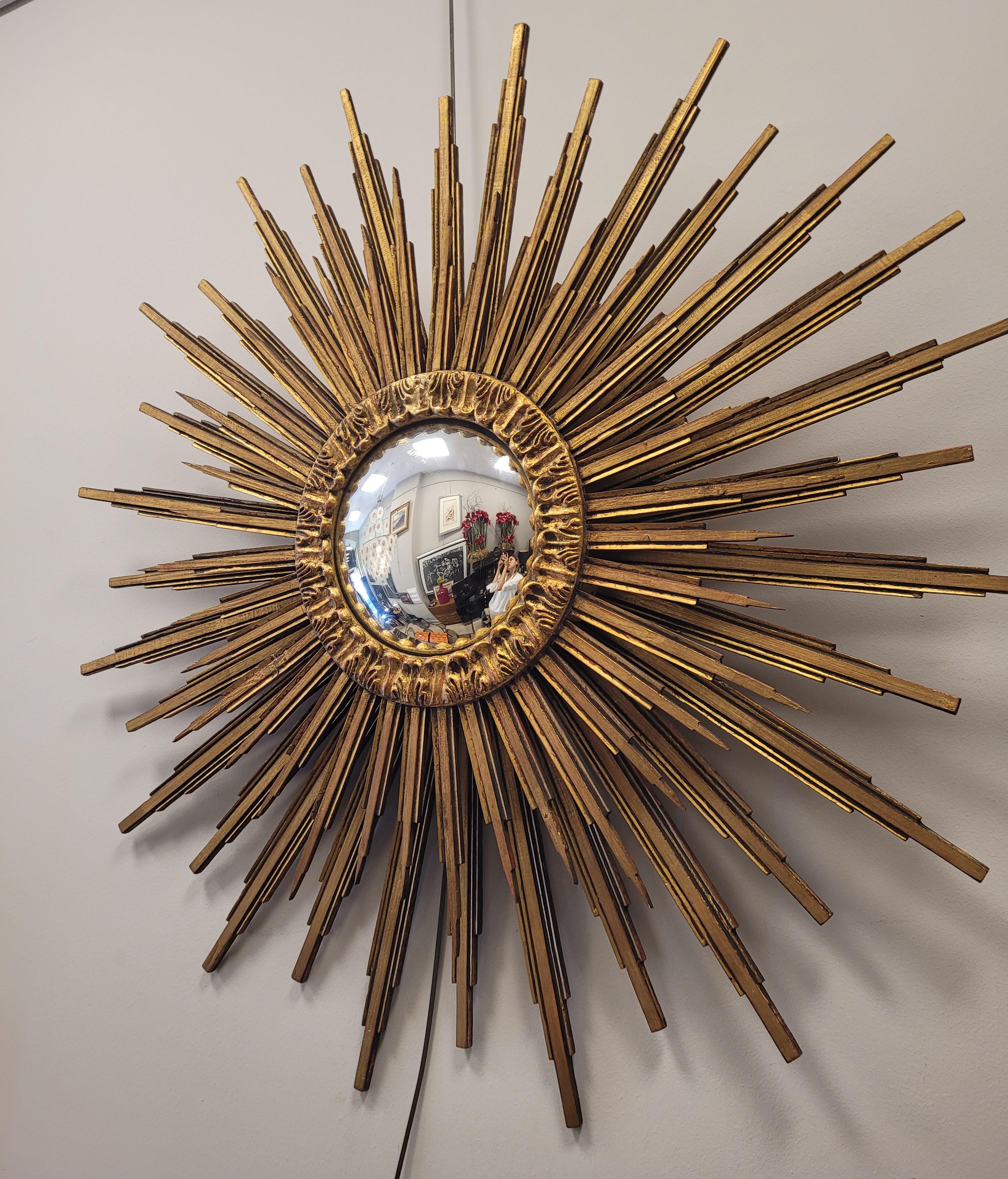 Superbe miroir convexe Sunburst en forme de soleil rayonnant, fabriqué en France dans les années 90, selon un style Art déco bien défini. Structure complète en bois sculpté et doré. Comme il est d'usage dans ce type de miroir, il comporte deux