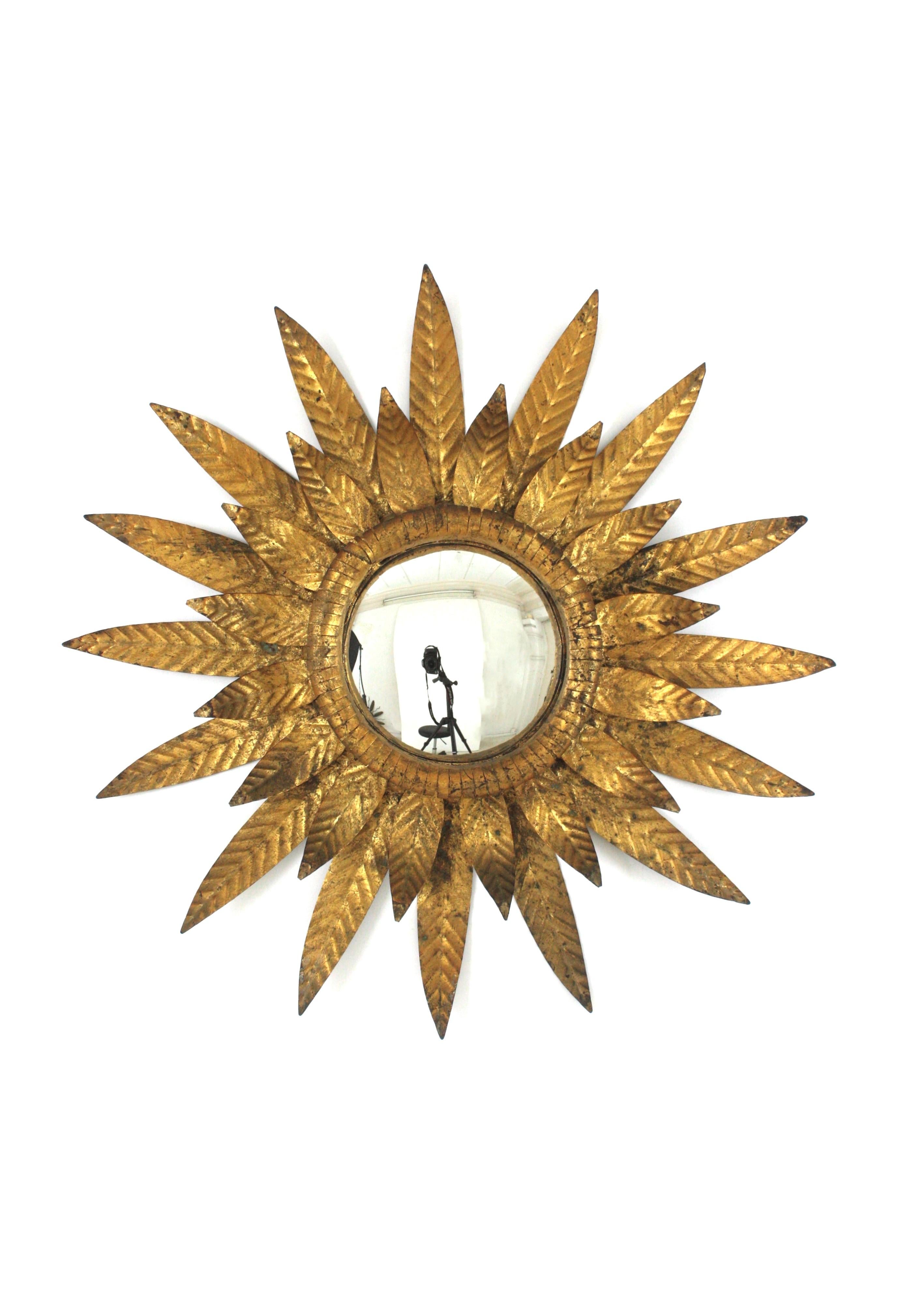 Hand-Crafted Gilt Convex Sunburst Mirror, Iron, Gold Leaf
Eye-catching Mid-Century Hollywood Regency sunburst mirror in gilt iron, Spain 1950s
Double layered foliage frame, convex glass and gilded finish in gold leaf. It has a glamourous patina