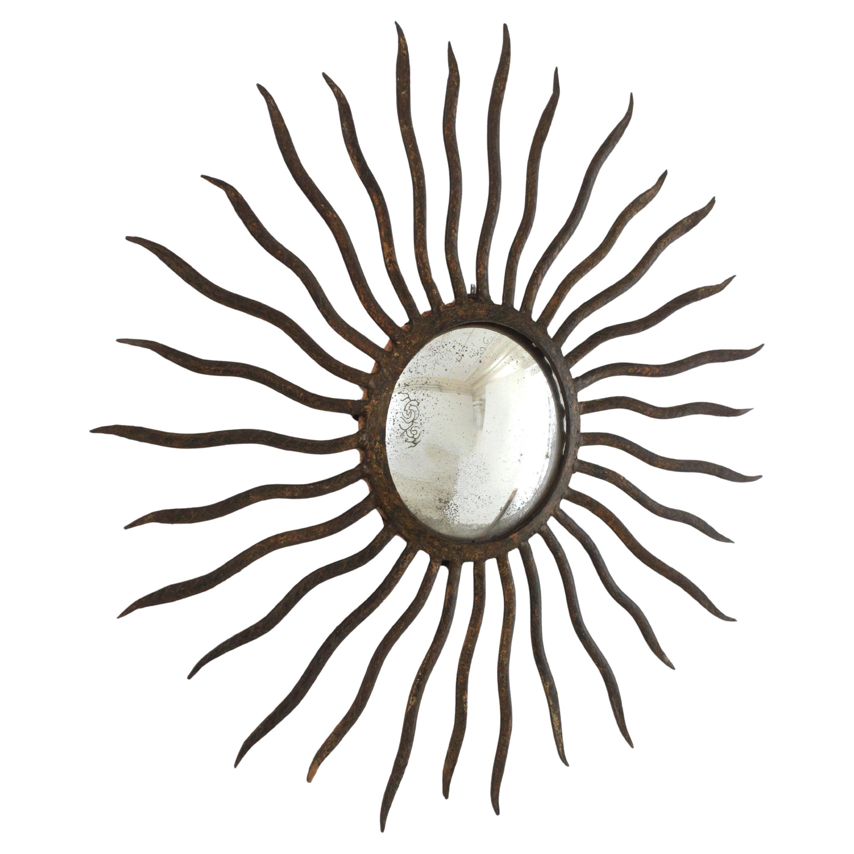 Sunburst mirror in the manner of Gilbert Poillerat, Parcel-Gilt Wrought Iron. France, 1940s.
This sunburst wall mirror has an eye-catching sunburst design with curly rays surrounding a central convex glass. Entirely made by hand in wrought iron.
