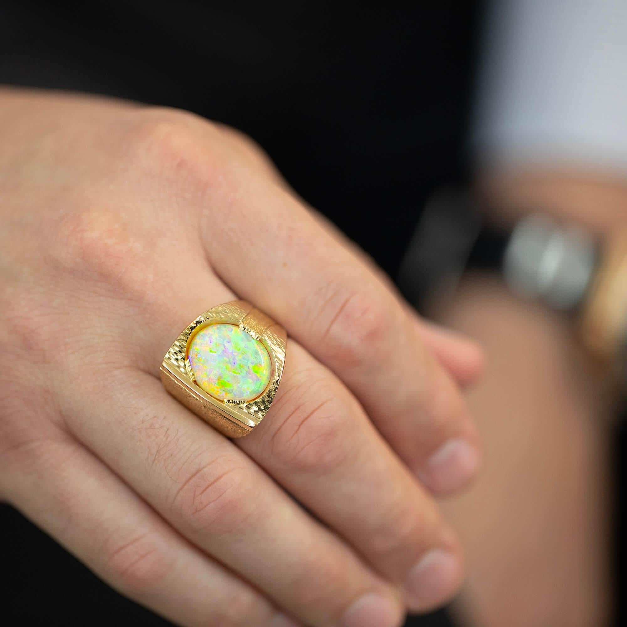 This 18k yellow gold ring grading from 5.79 to 23.5mm in width with an elaborately textured finish, set with a stunning light, low cabochon cut Coober Pedy Opal. Hallmarked and stamped with marker mark by renowned jeweller, Manfred Lorenz.

Opal –