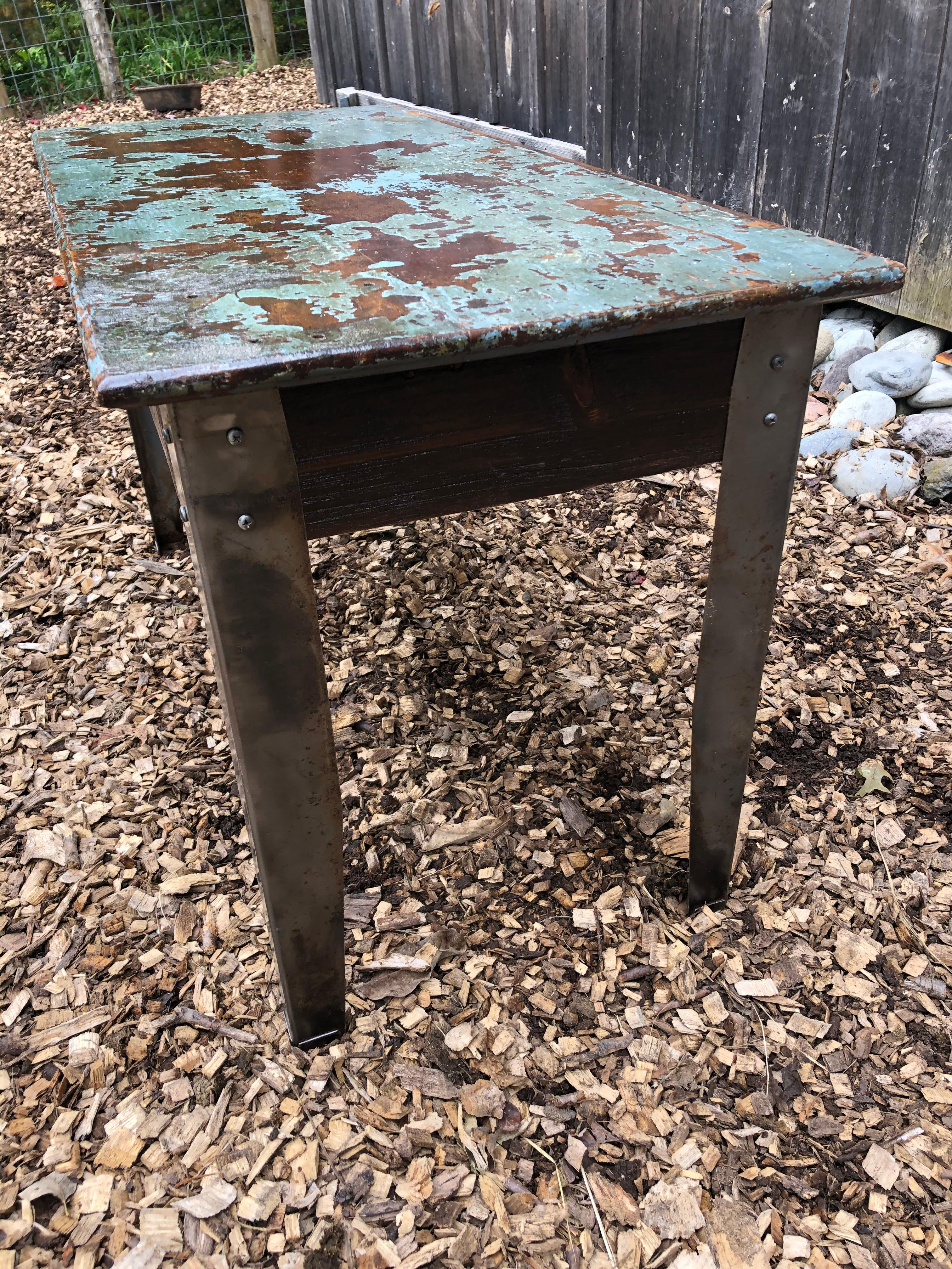 A one of a kind industrial table having wooden top with copper tones underneath a distressed turquoise paint. The legs are aluminum and give a great looking contrast to the top.
 