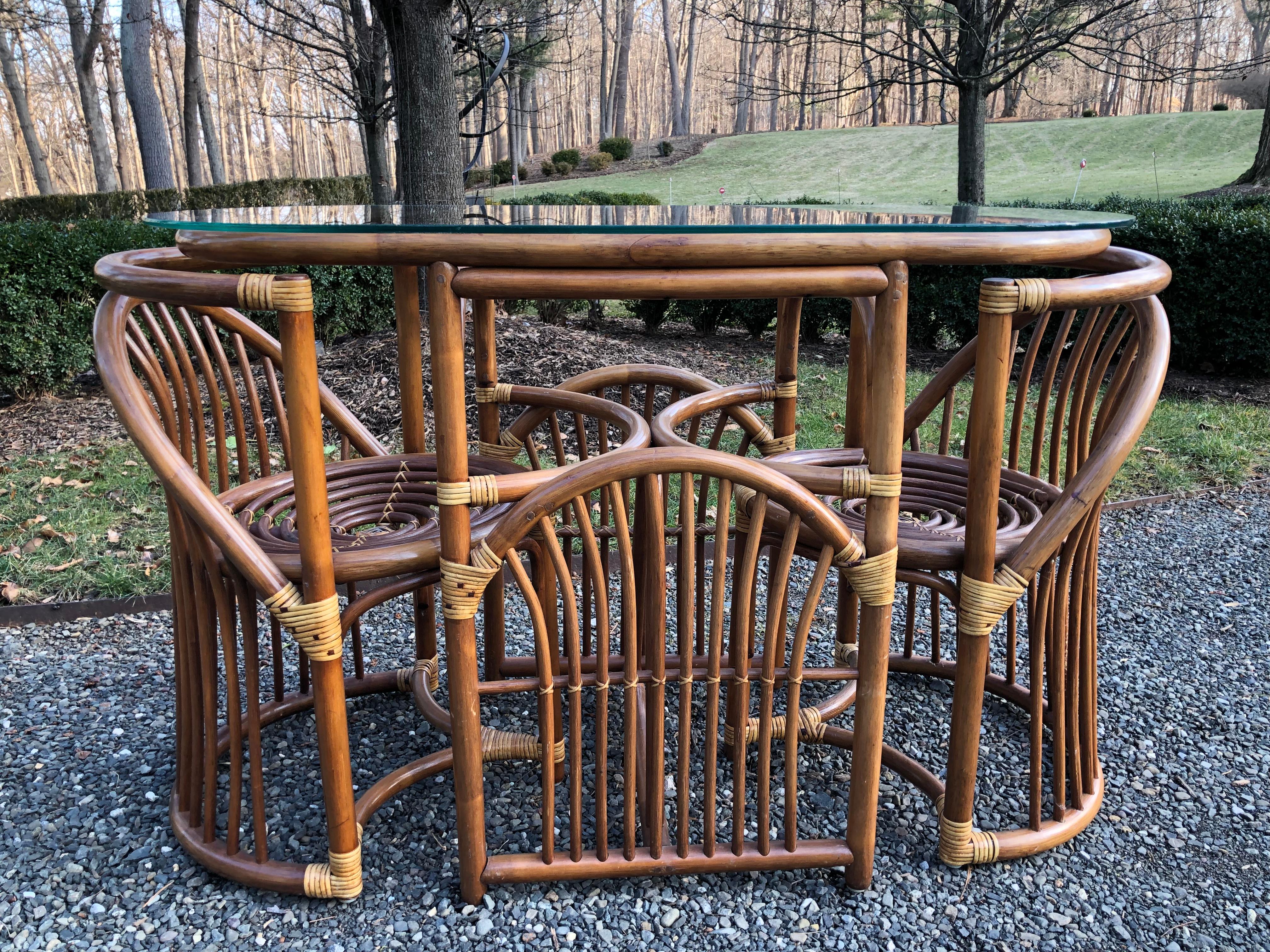 Midcentury bentwood and rattan dining set for two with glass top. Matching chairs have seats with concentric circles. The bentwood is a great shade of caramel and has nice patina. The table has an oval glass top and measures 44” wide x 22” deep x