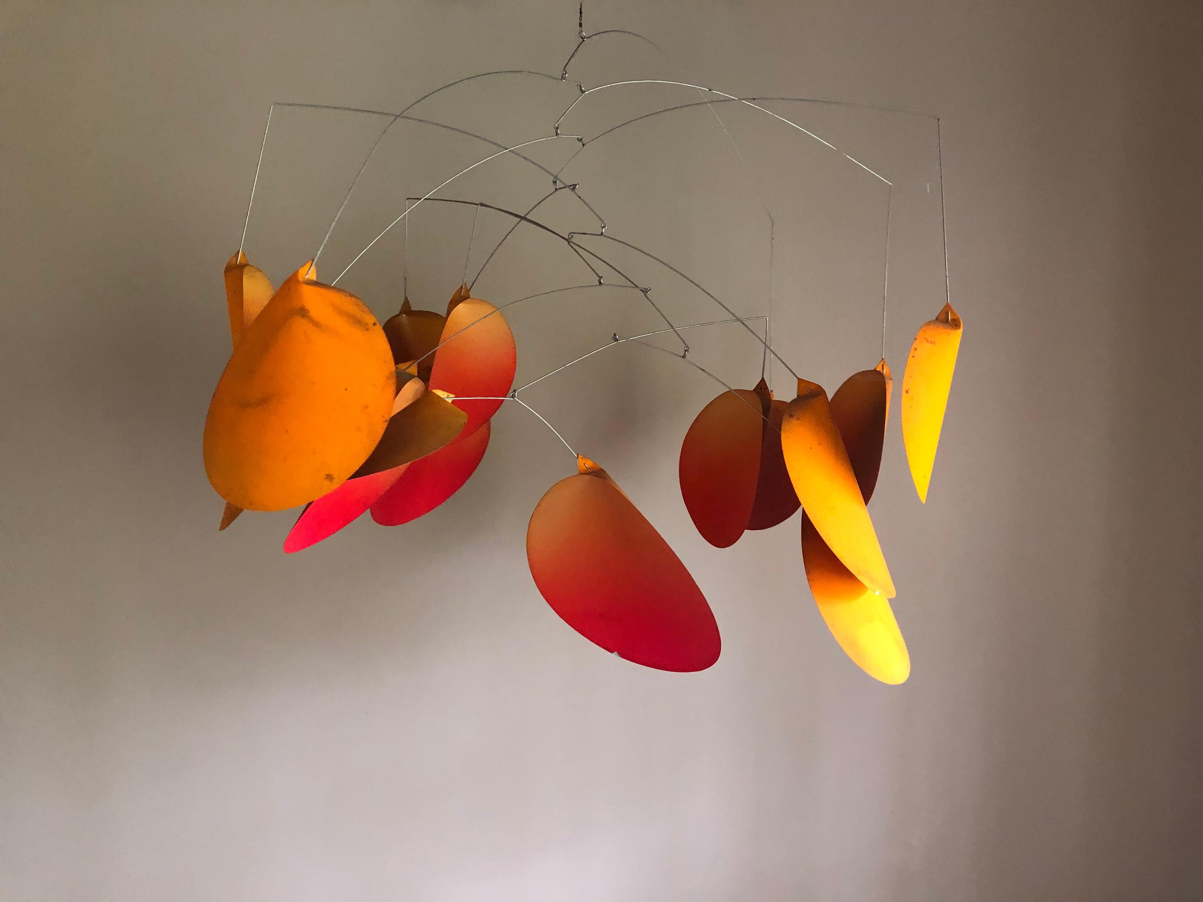 A cool tin and wire kinetic mobile hanging sculpture having individual discs where the orange paint turns red towards the bottom for added visual punch. Weighs about 2 lbs.