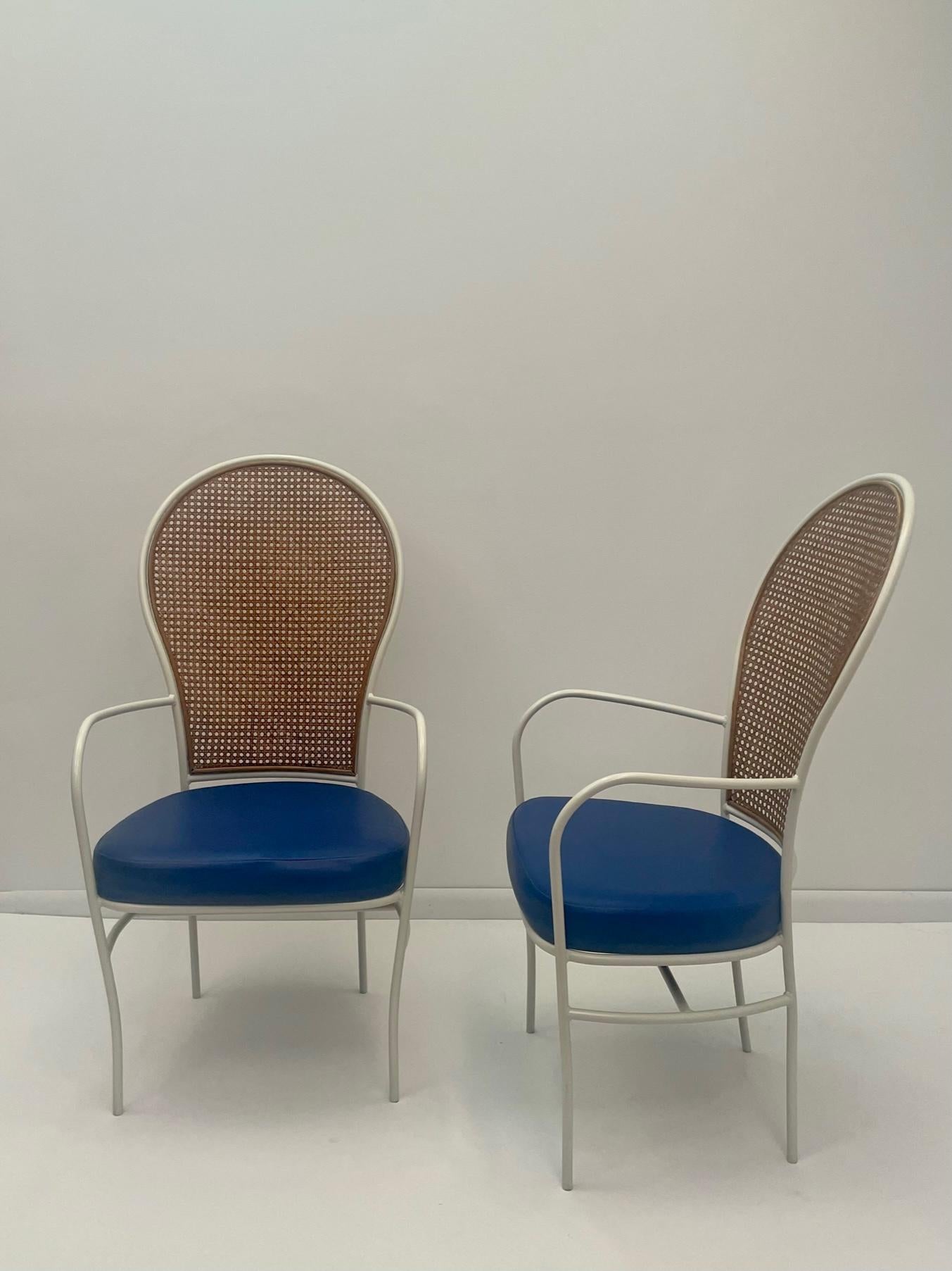 Cool Mid-Century Modern pair of Milo Baughman armchairs having painted white iron frame with handsome caned backs and original blue vinyl seats. Arms are thin and elegant as are the legs. 
Arm height 26.