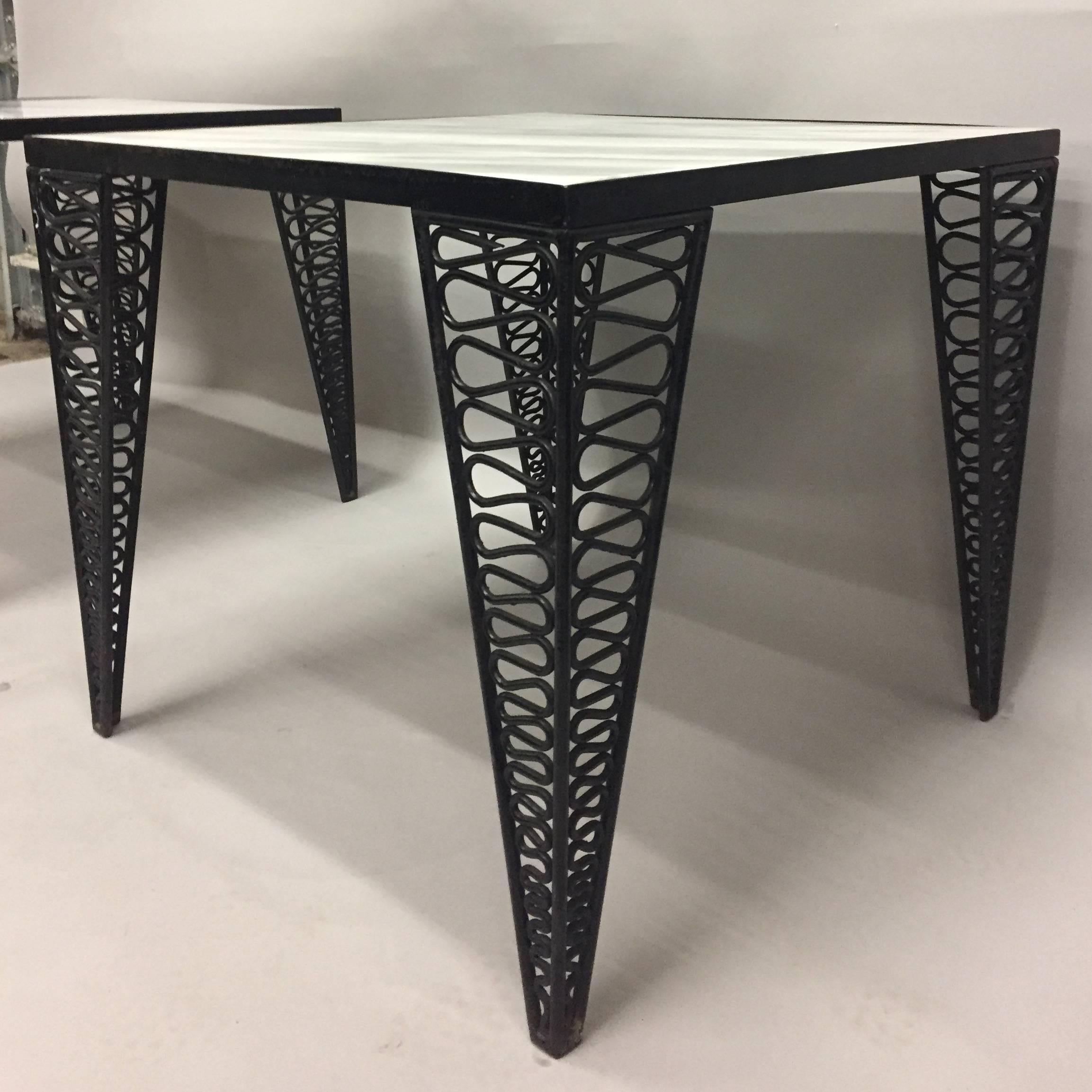 Two sophisticated end tables having black iron bases by Tempestini for Salterini, stylish triangular legs with decorative mesh like pattern, and sleek white and grey veined marble tops.