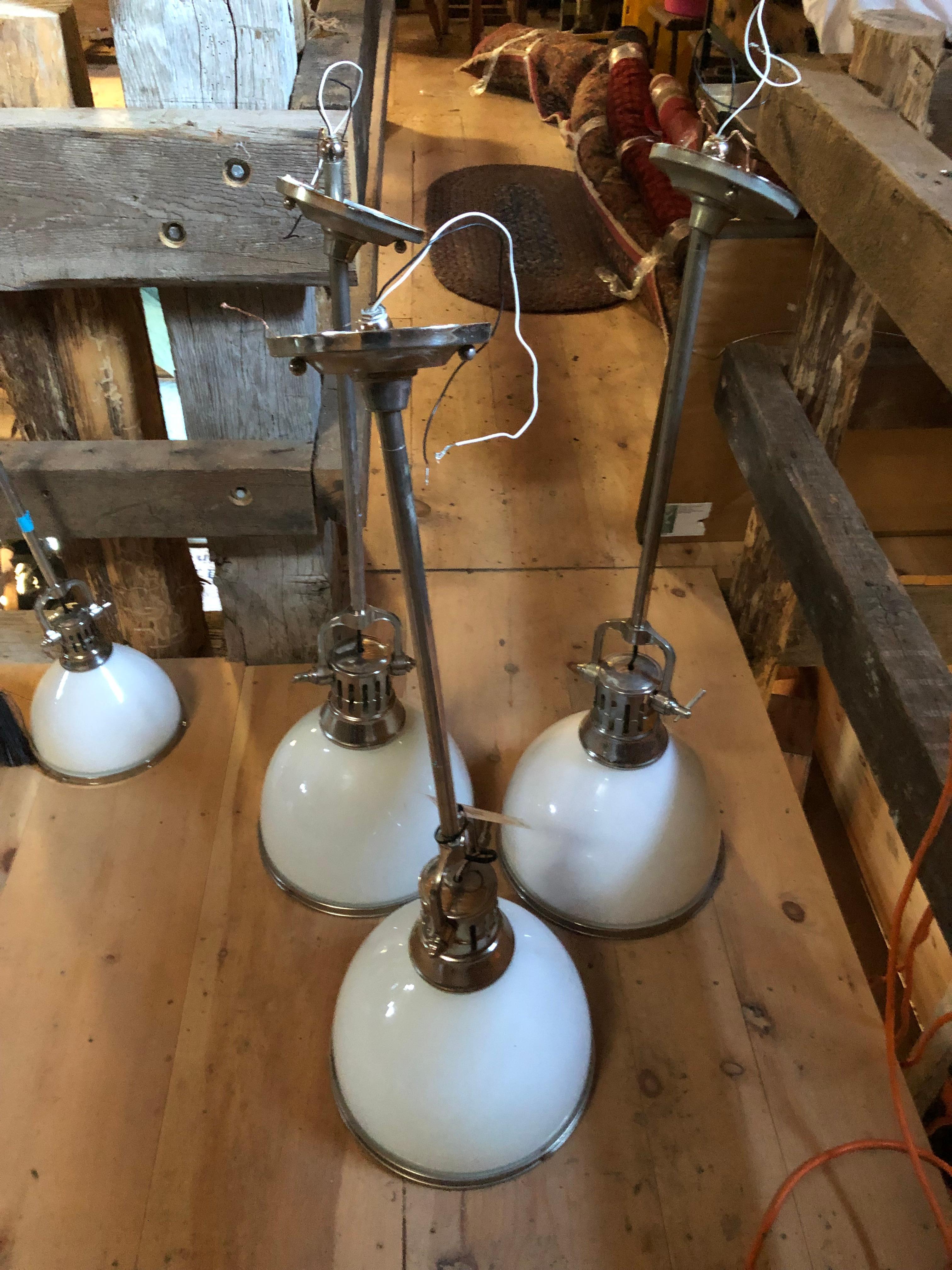 Striking set of 3 Hudson Valley Lighting Randolph single light industrial pendants having chrome stems and white opaque glass shades, closed at the bottoms with chrome ring frames.
Note: there are 2 smaller matching pendants available.