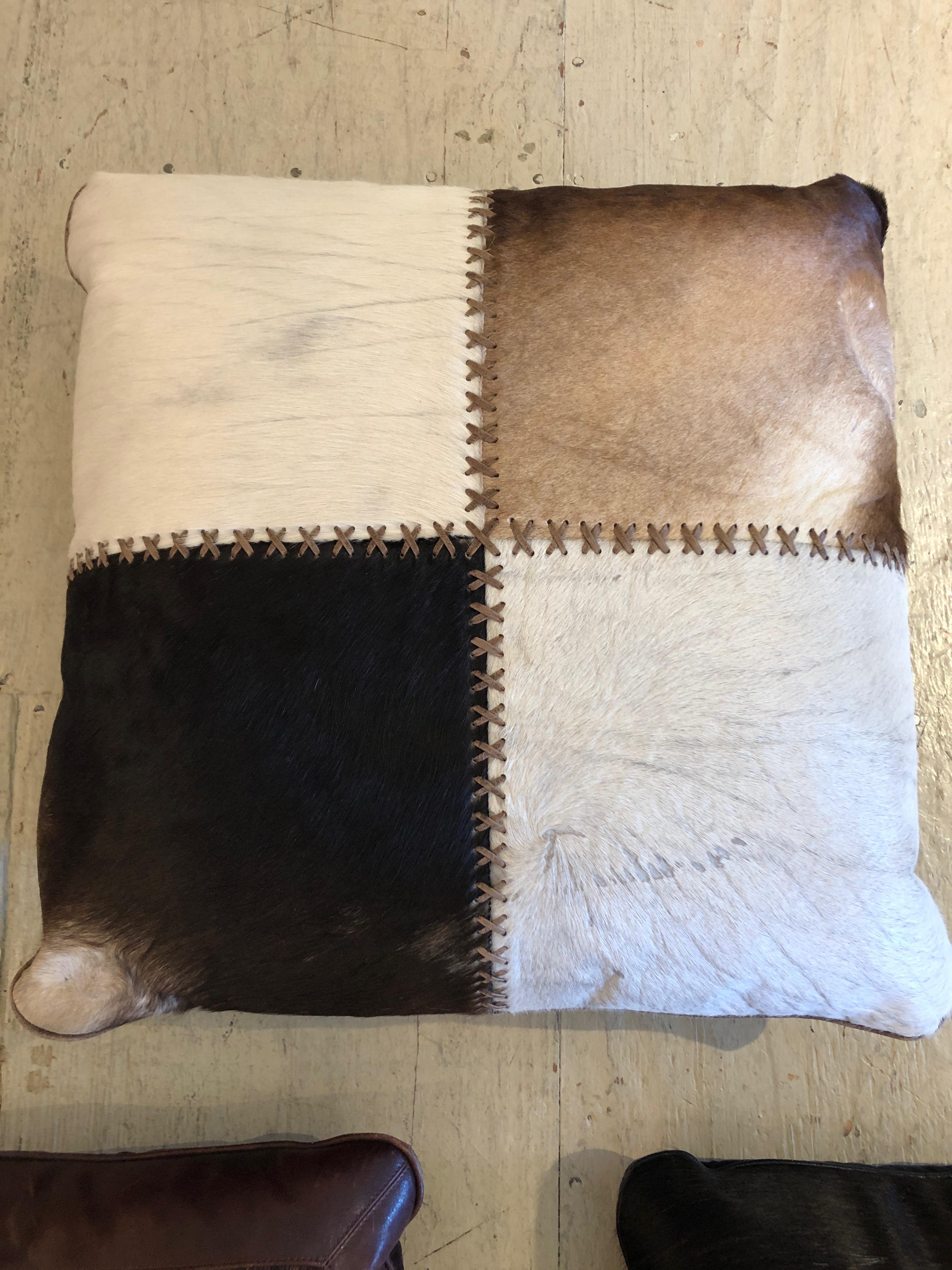 Three very handsome handmade custom pillows having an assortment of cowhide, leather and decorative stitching in warm browns, cream, black and metallic leather. Two small pillows are 16 x 16 x 3.5.