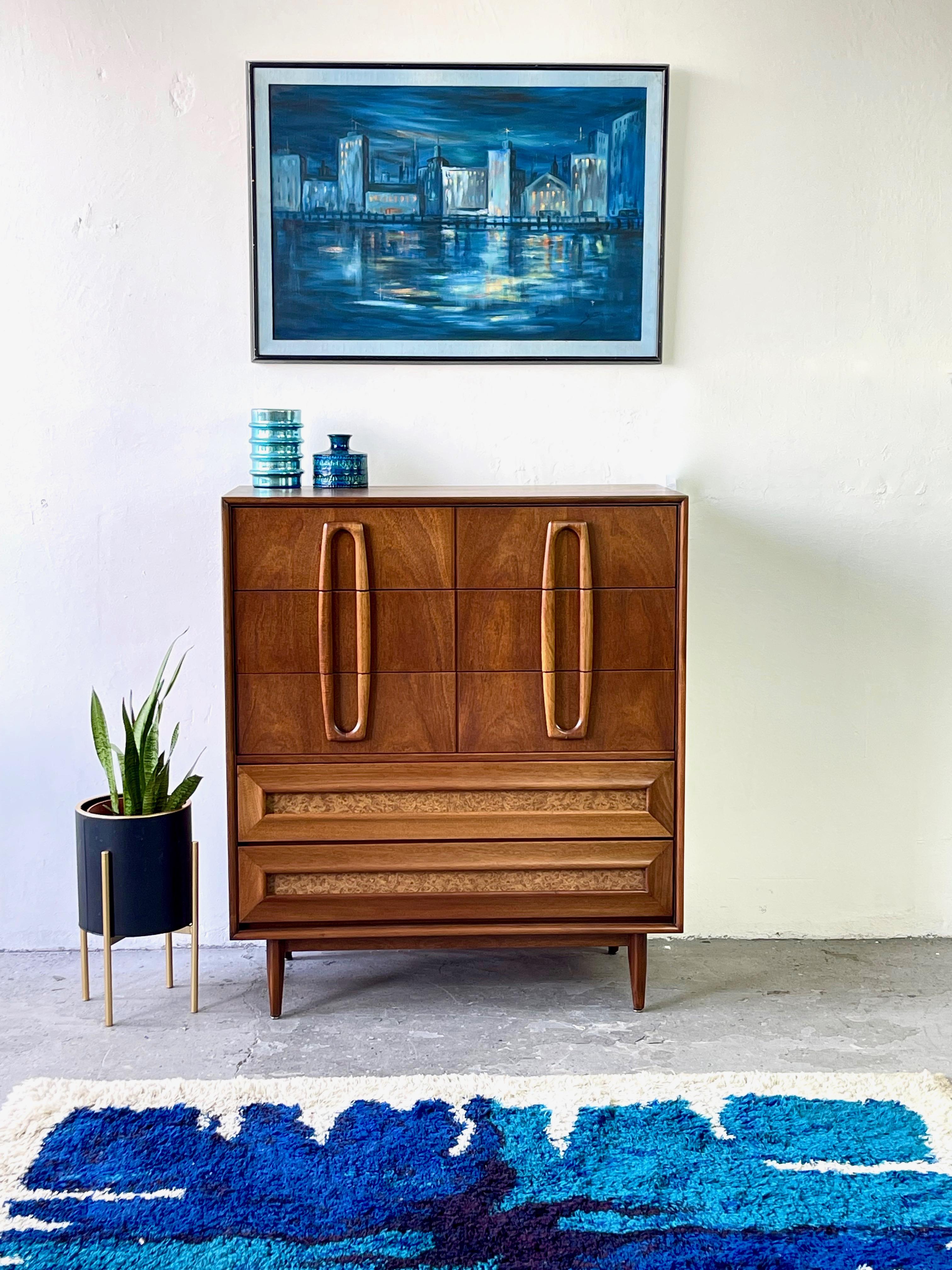 An unbelievably designed mid century modern highboy dresser featuring gorgeous walnut woodgrain alongside burl laminate accent delicately sculpted pulls!

No significant imperfections to note! All drawers function smoothly. 

Measures: 40.25