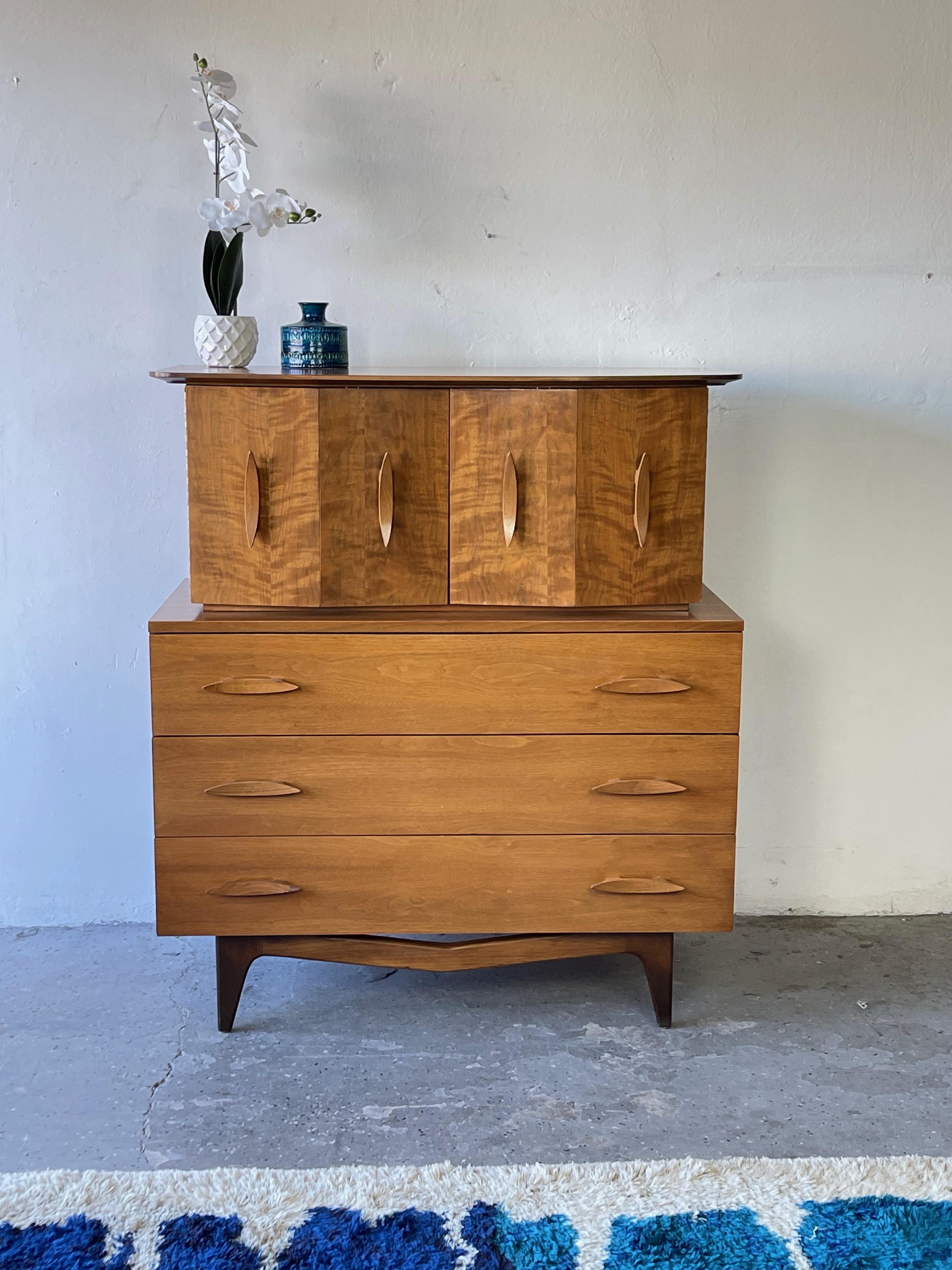 An unbelievably designed mid century modern highboy dresser featuring gorgeous carved/ sculpted wood handles! And beautiful wood that glimmers in the light 

In wonderful original vintage condition no notable imperfections

 Measures: 42