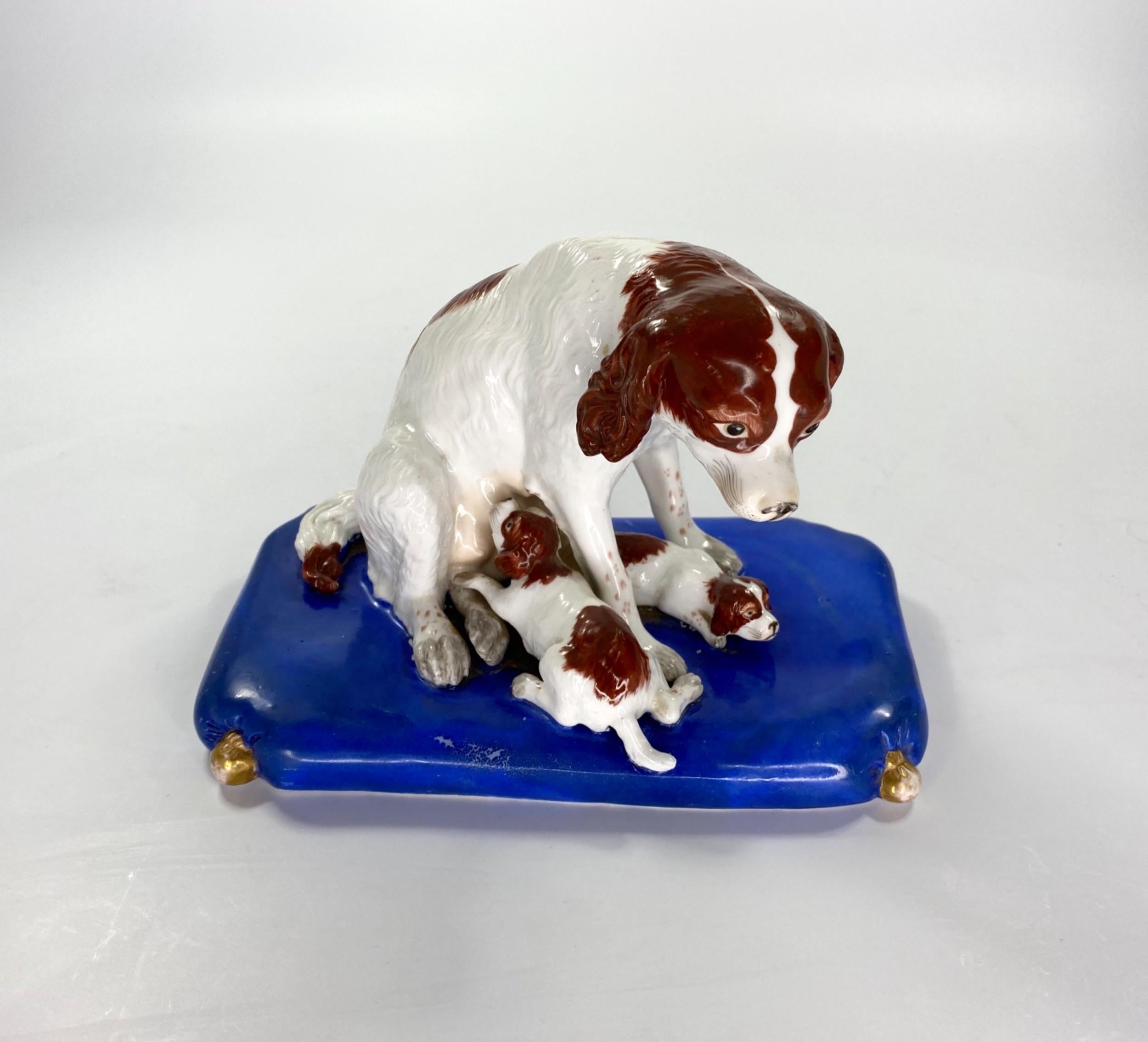 Copeland and Garrett porcelain group, circa 1840. Charmingly observed, as a Spaniel seated, whilst one of her puppies suckles upon her, and her other puppy lies between her front legs. The hair finely detailed, and heightened with brown enamelled