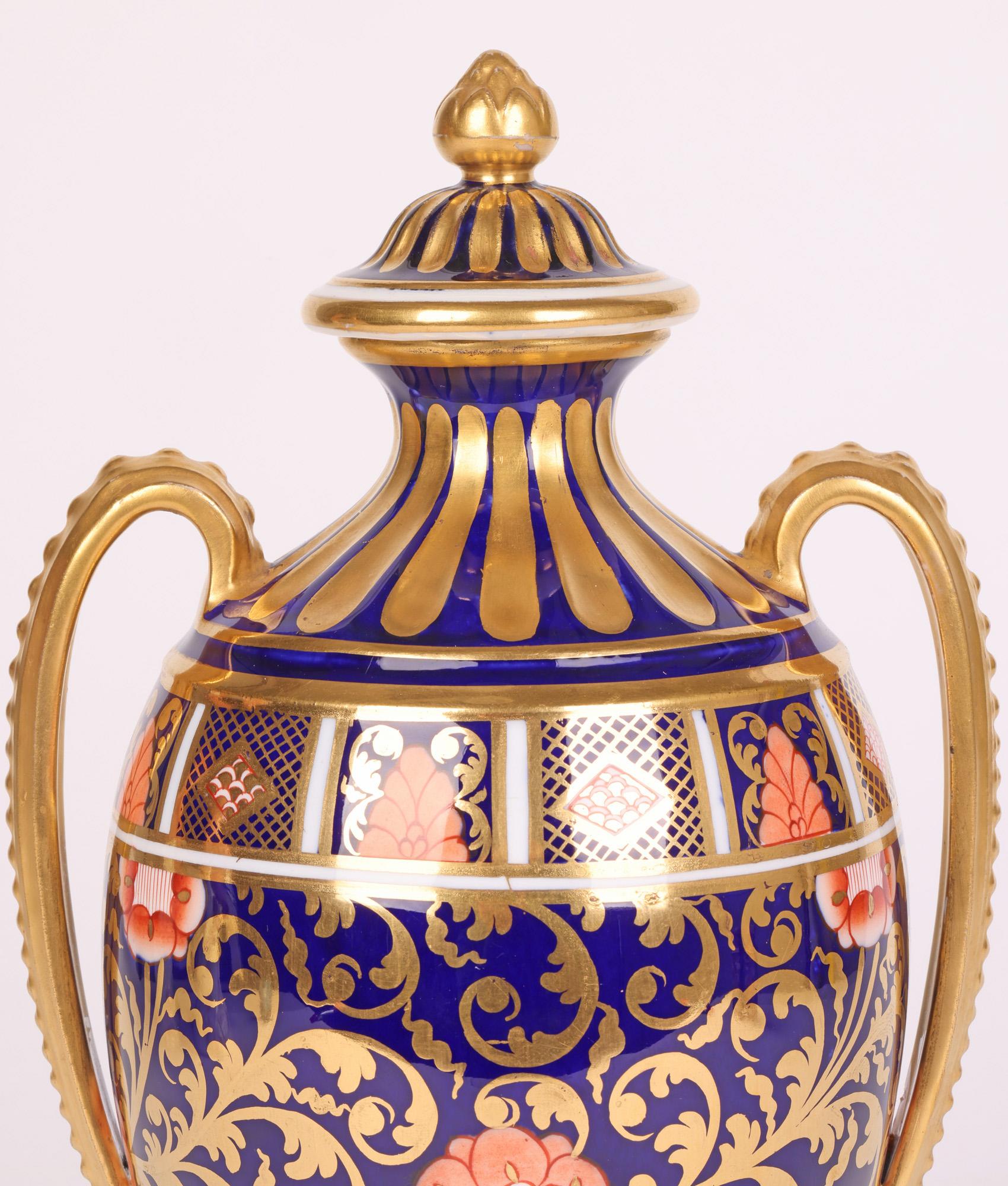 Eine atemberaubende antike Porzellan-Urne in Form einer Vase mit zwei Henkeln und einem Deckel, dekoriert mit einem Imari-Muster von Copeland, England, aus dem frühen 20. Jahrhundert. Die Vase steht auf einem quadratischen Sockelfuß mit schmalem