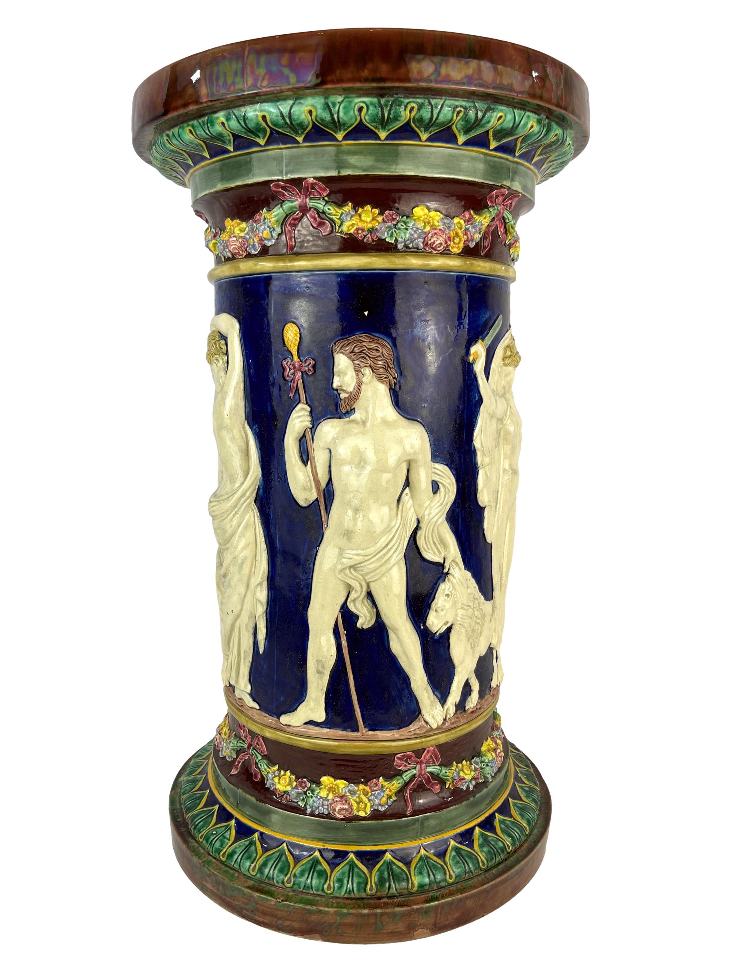 W. T. Copeland & Sons Majolica, the column-form pedestal molded in high relief with Classical figures including Diana the Huntress wielding a sword, with floral garlands tied with pink glazed ribbons to the top and base, on a cobalt blue glazed