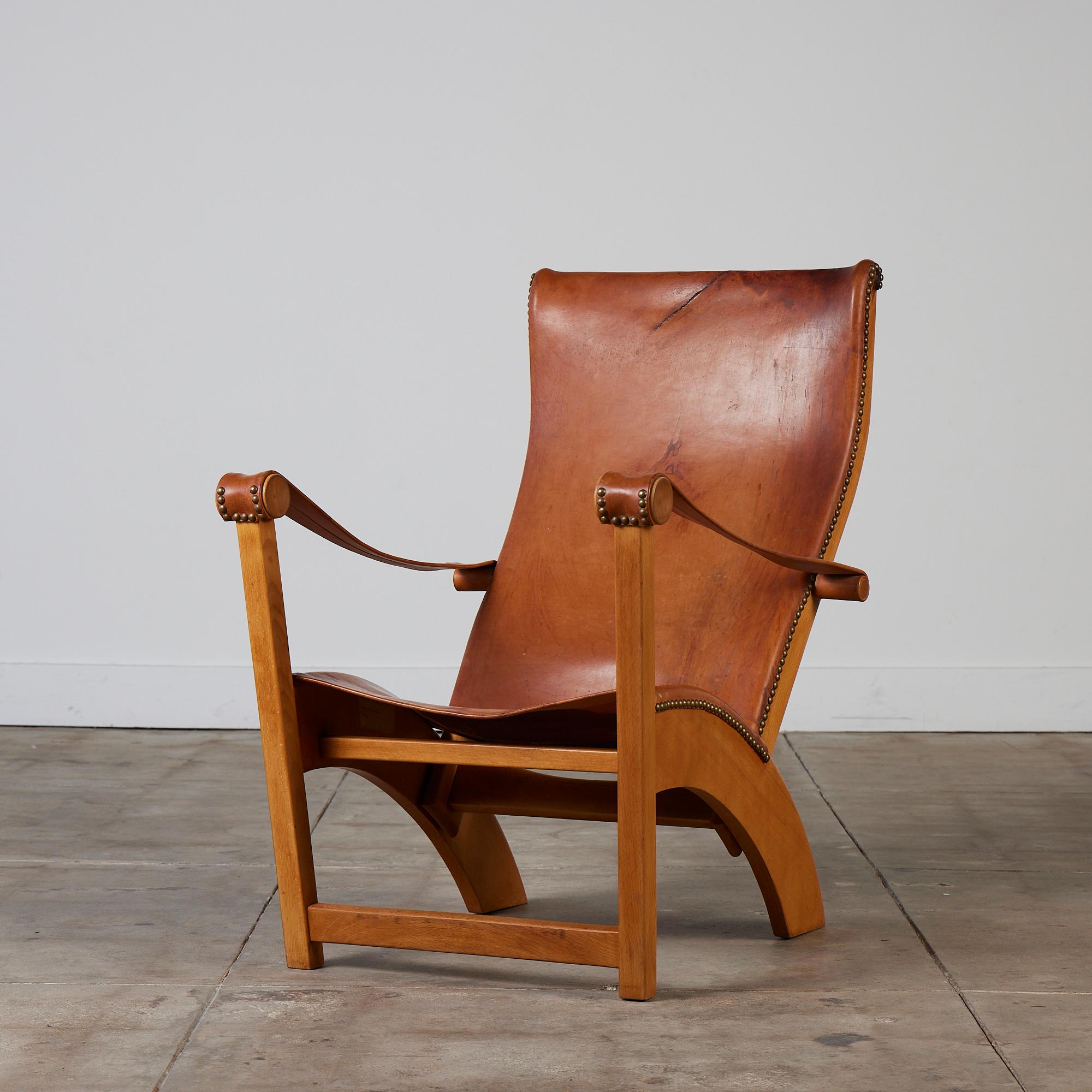 An impressive lounge chair by Mogens Voltelen for Niels Vodder, c.1936, Denmark. This comfortable lounge chair features a stunning sculptural beech wood frame and legs. The aged cognac saddle leather back, seat and armrests are rich with unique