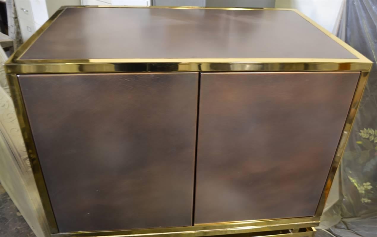 This European cabinet is retro at its finest. The cabinet features a copper case accented by brass framing. There is a lower tinted glass surface, doors on touch latches and an interior shelf.