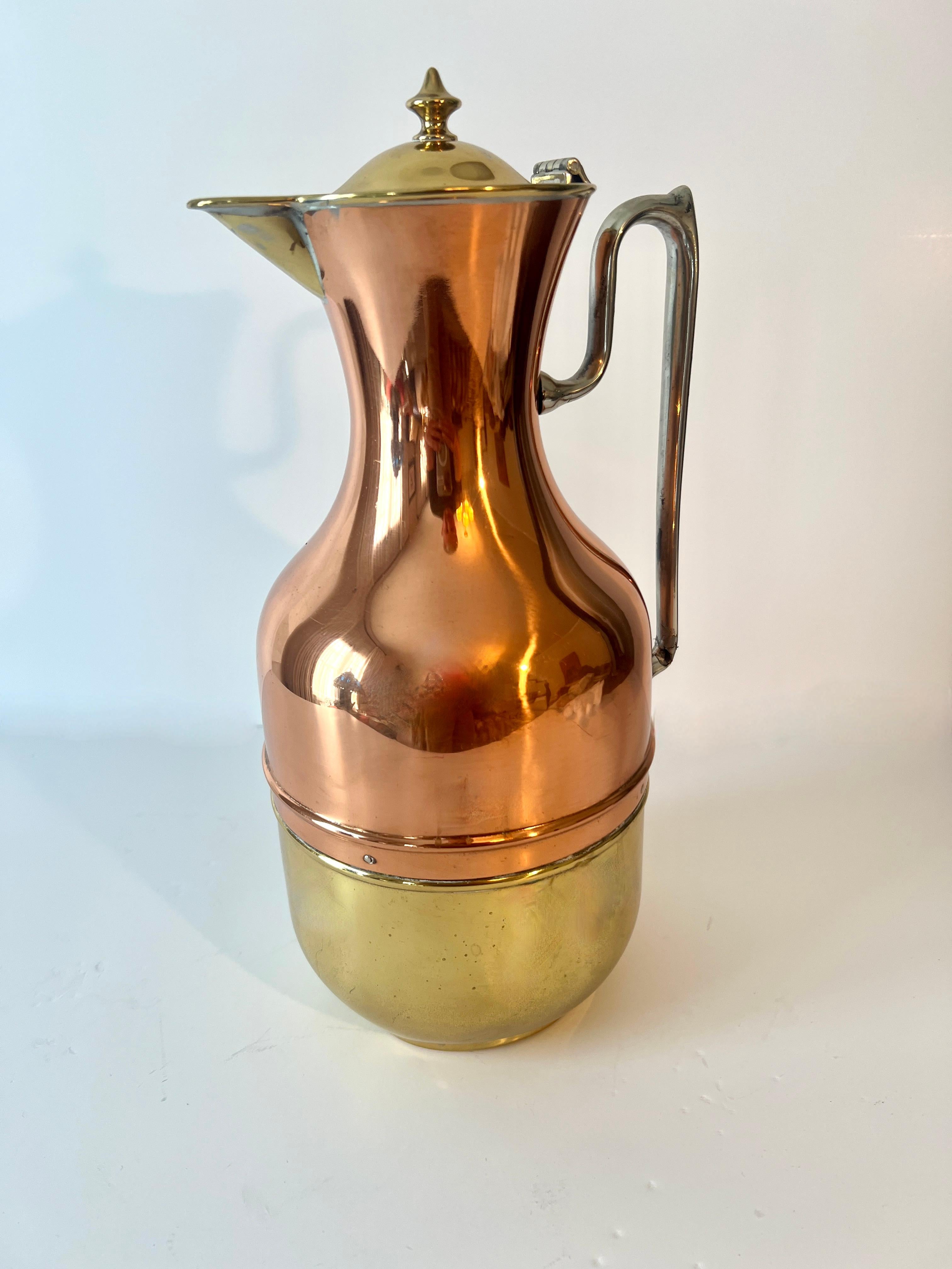 Ein eleganter und moderner Krug aus Kupfer und Messing mit Edelstahl- oder Chromgriff und Klappdeckel.  Diese architektonische Schönheit ist nicht nur funktional für Säfte und Cocktails, für die Bar, sondern auch glasisoliert für das Servieren von